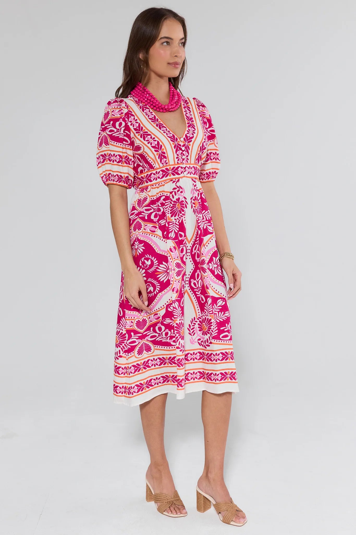 Woman wearing a pink and white patterned dress on a gray background