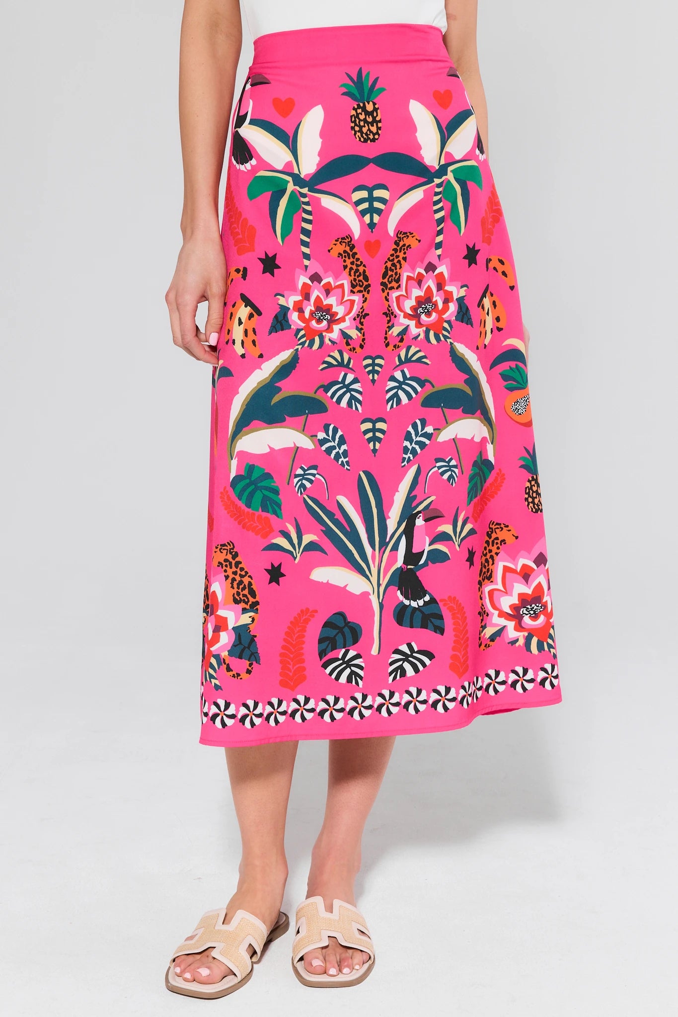 Person wearing a bright pink skirt with tropical pattern on a white background