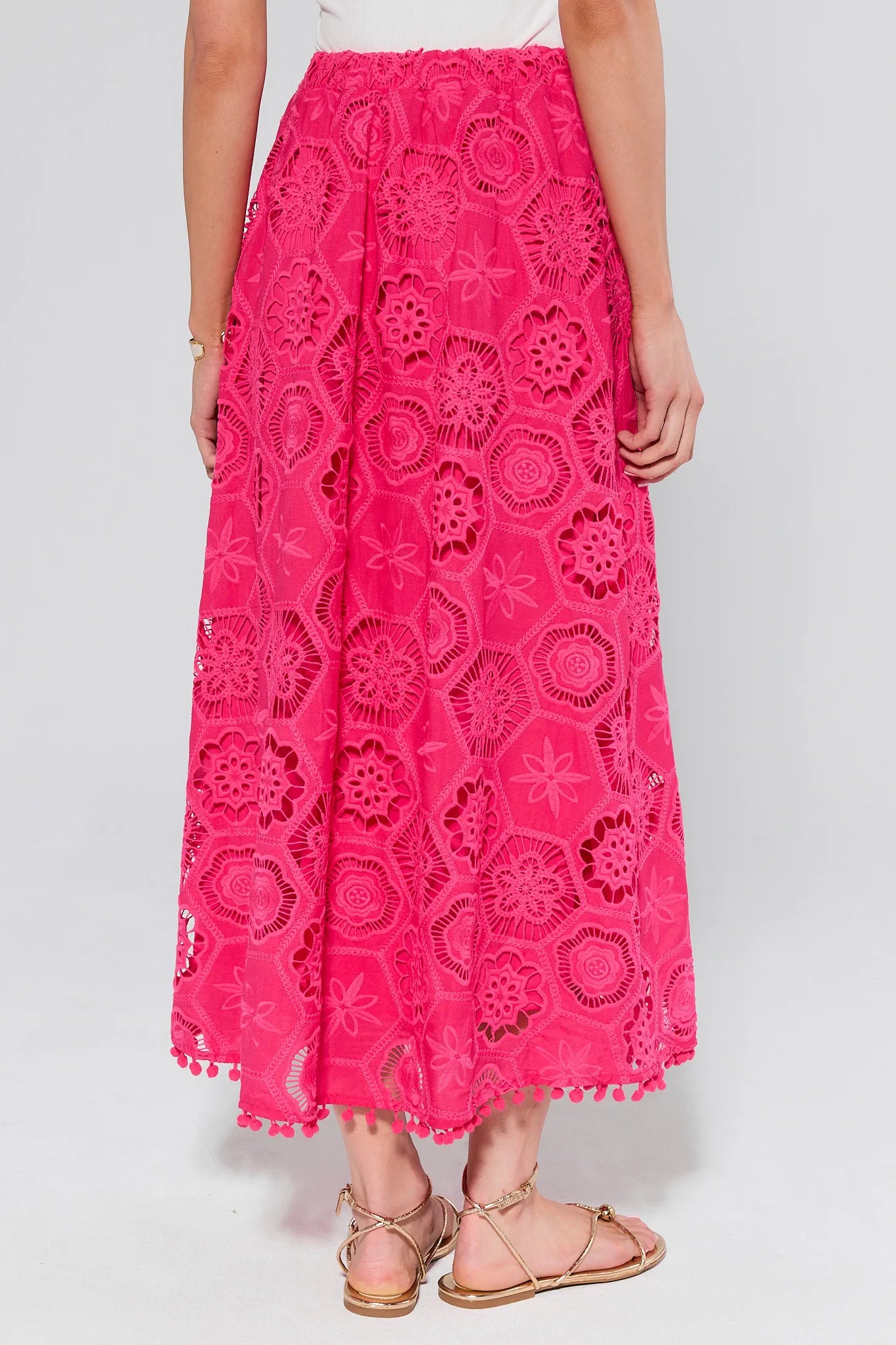 Person wearing a bright pink lace skirt on a white background