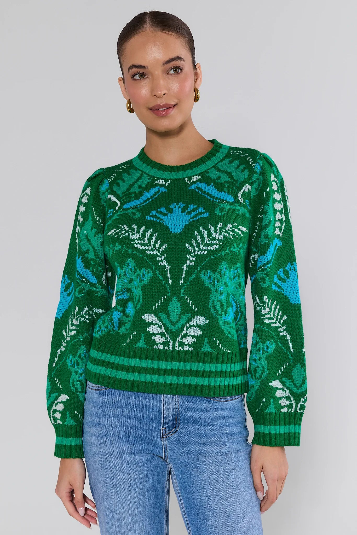 Woman wearing a green patterned sweater against a plain background