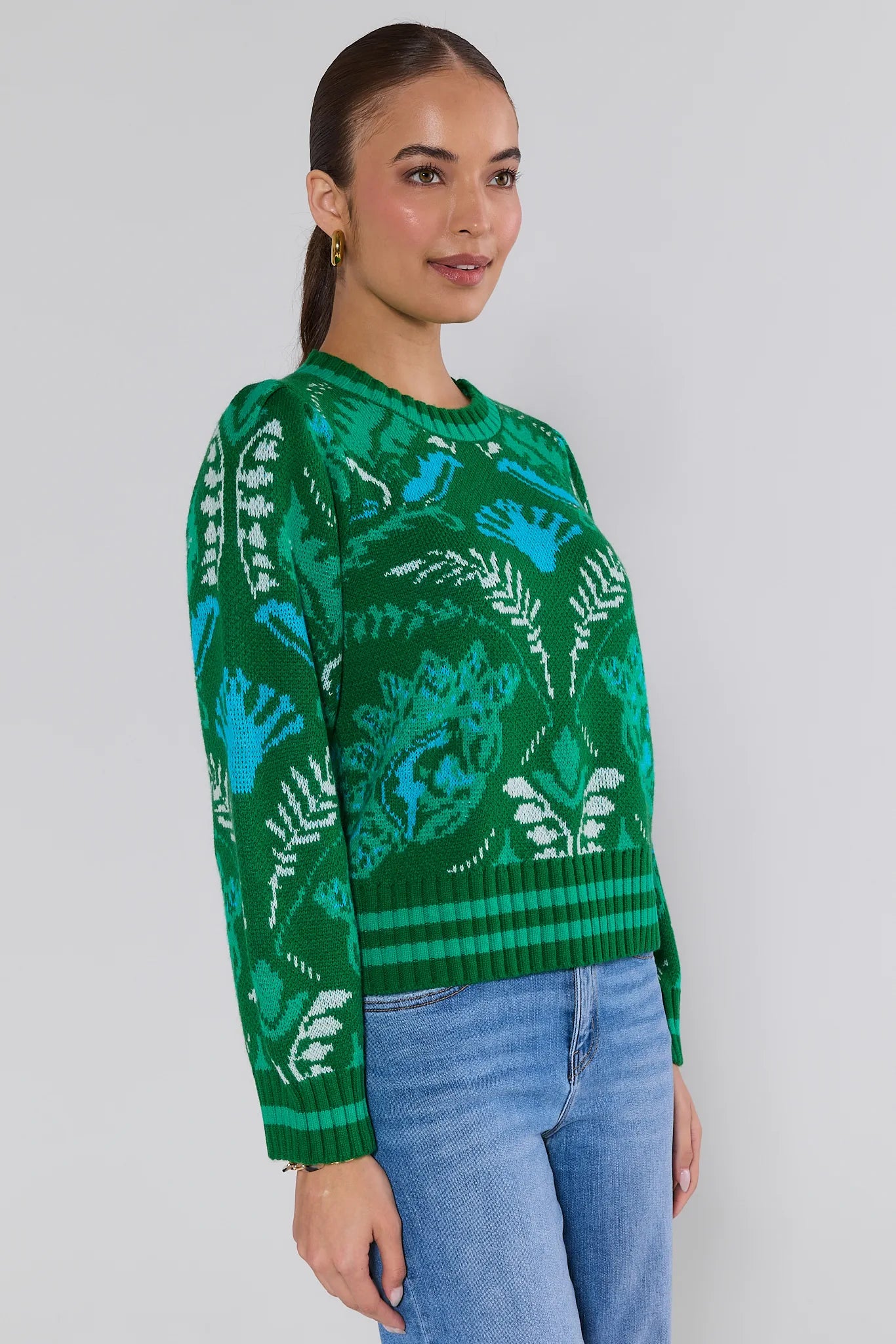 Woman wearing a green patterned sweater against a plain background