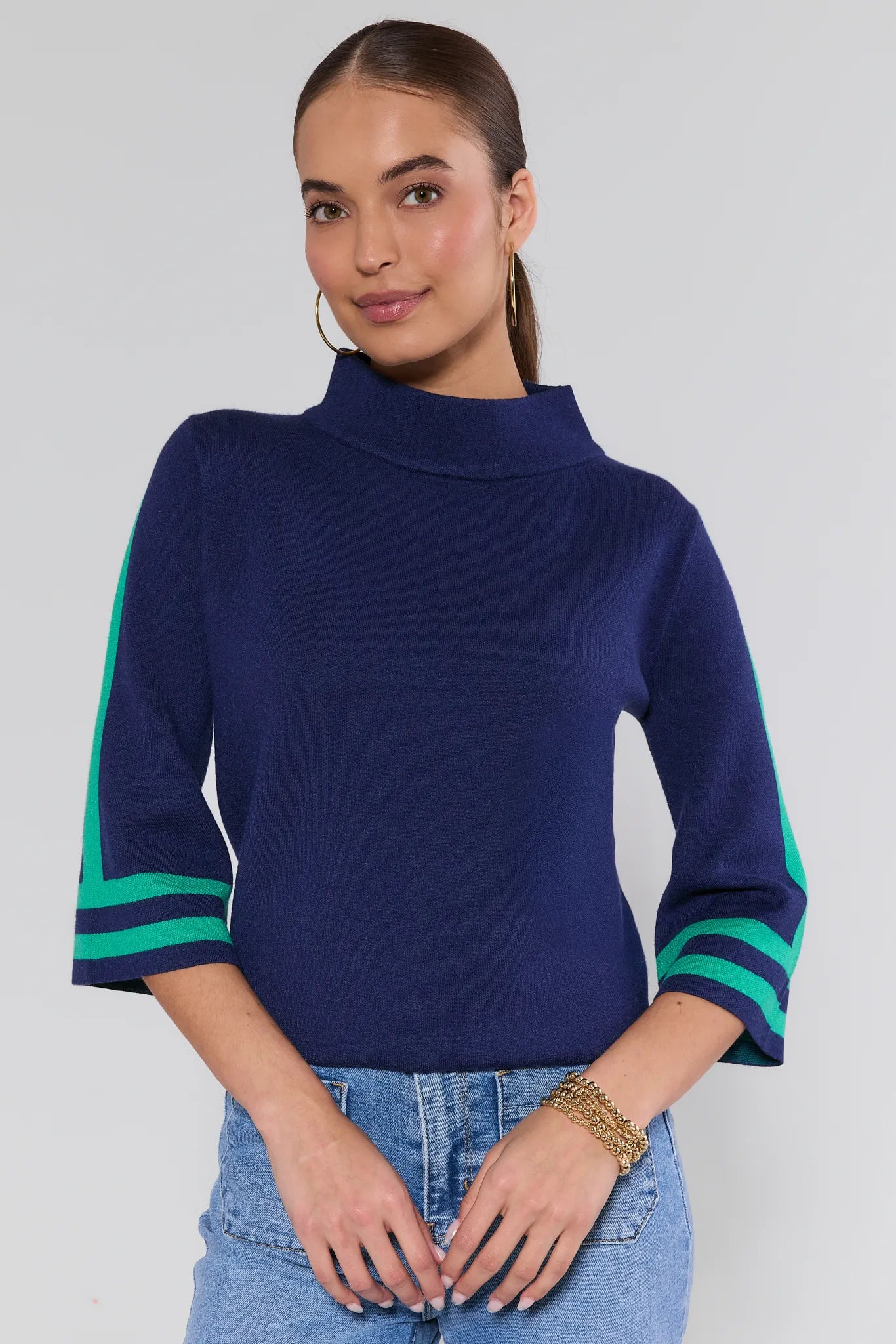 Woman wearing a navy sweater with green accents on a plain background