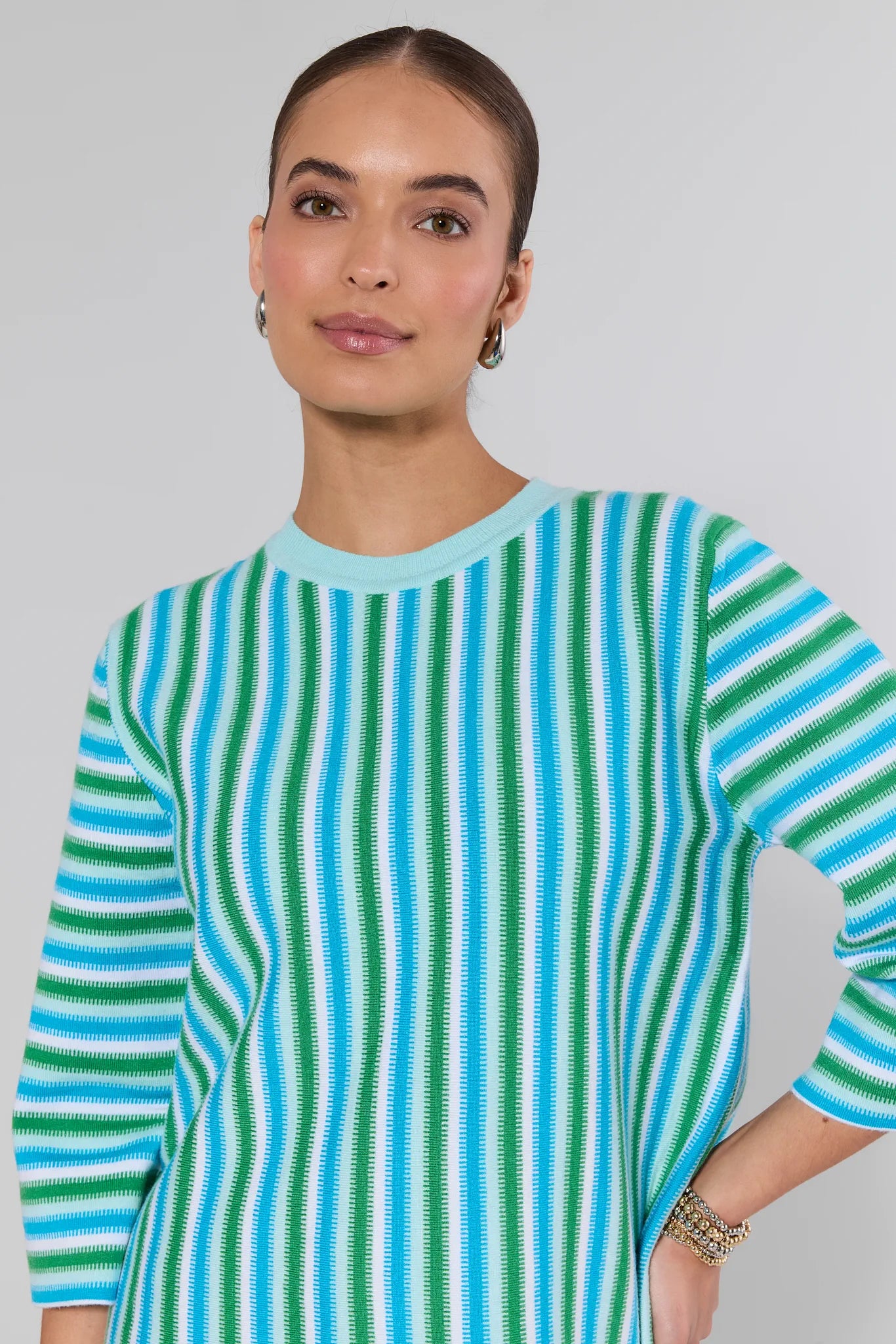 Woman wearing a blue and green striped sweater against a gray background