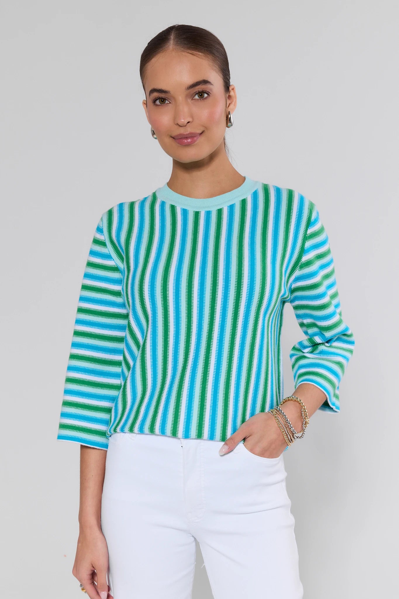 Woman wearing a blue and green striped sweater against a plain background