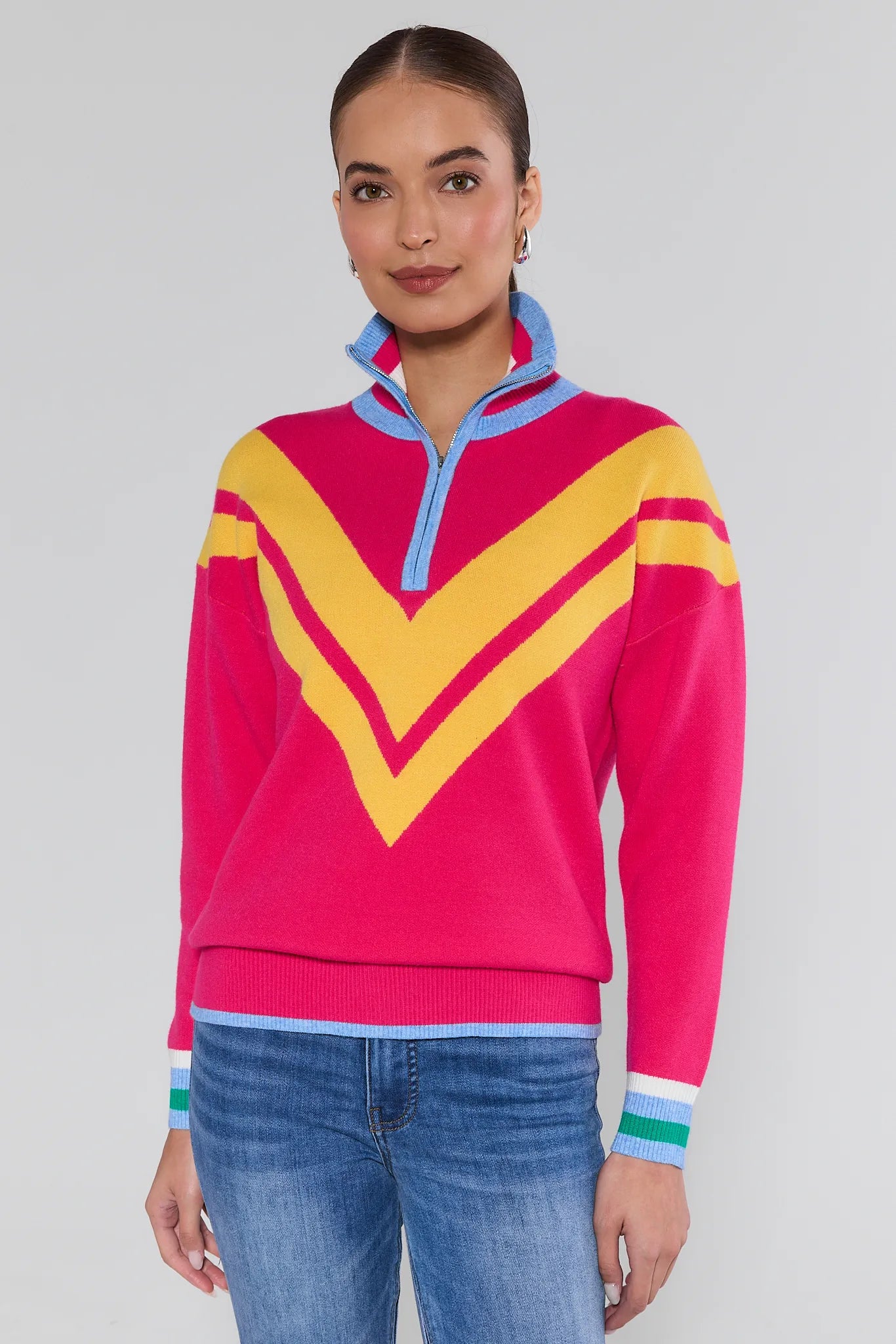 Woman wearing a colorful sweater with a large yellow V-shaped design on a plain background