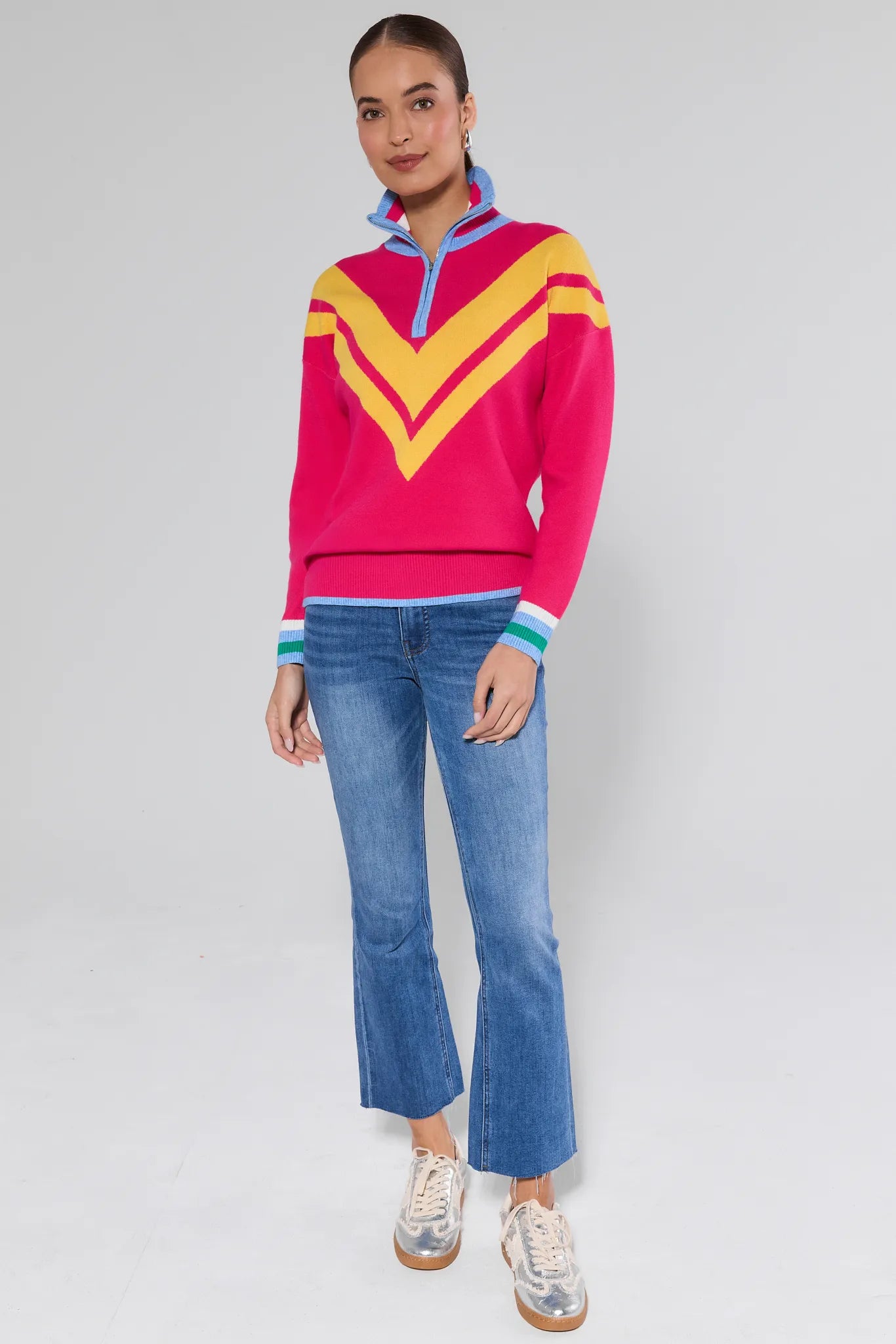 Person wearing a colorful sweater and blue jeans on a plain background