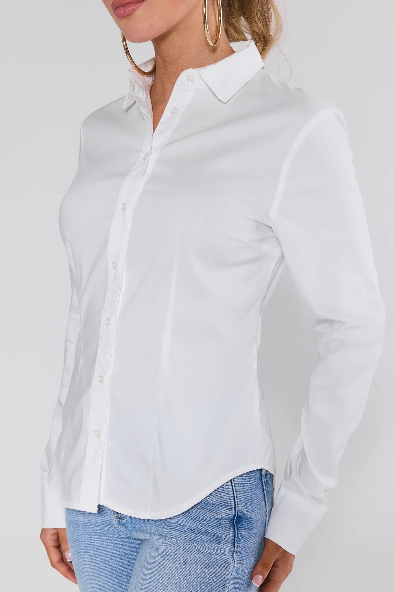 Woman wearing a Pacey White Button Up Top and light blue jeans against a plain background