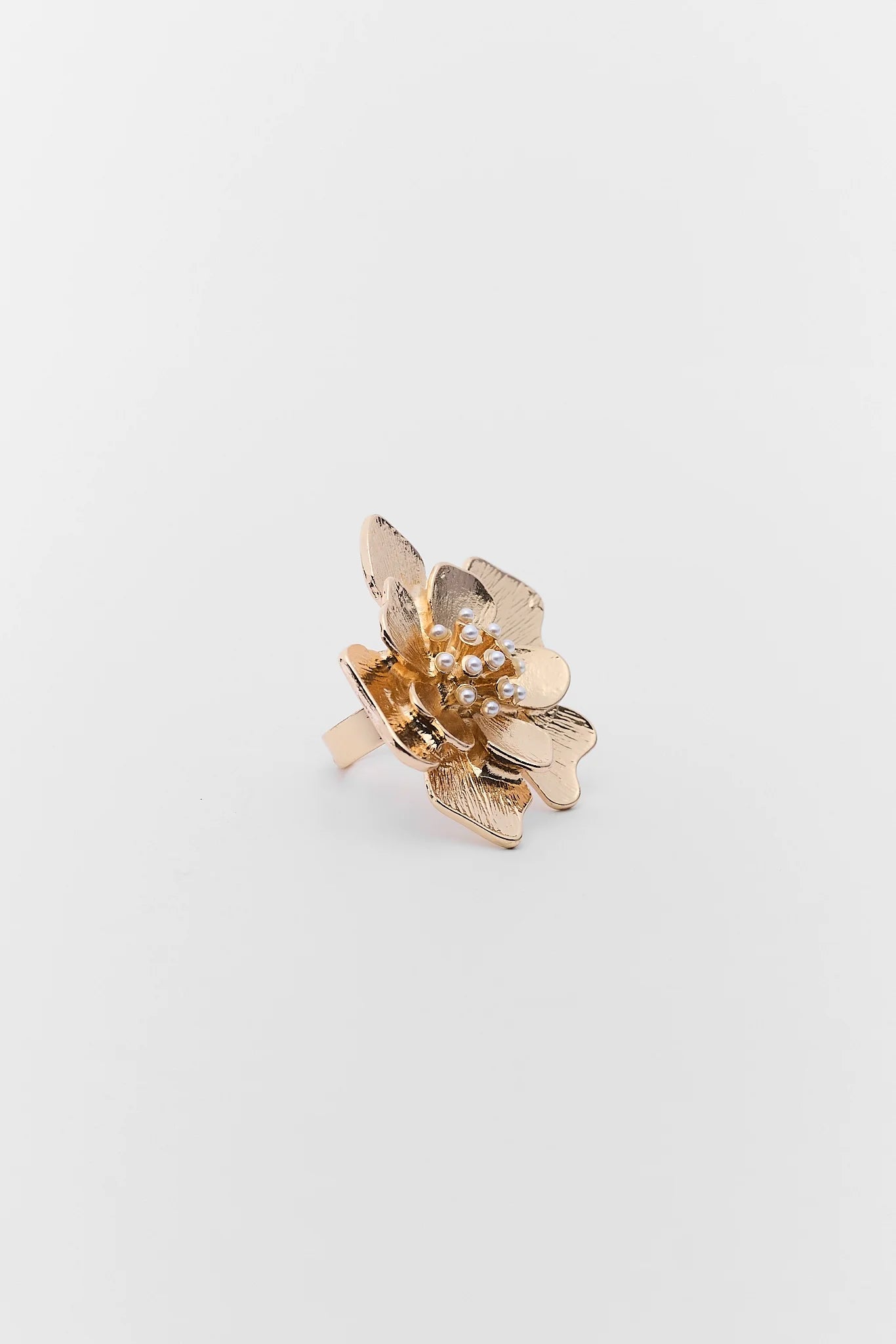 Gold floral earring on a light gray background
