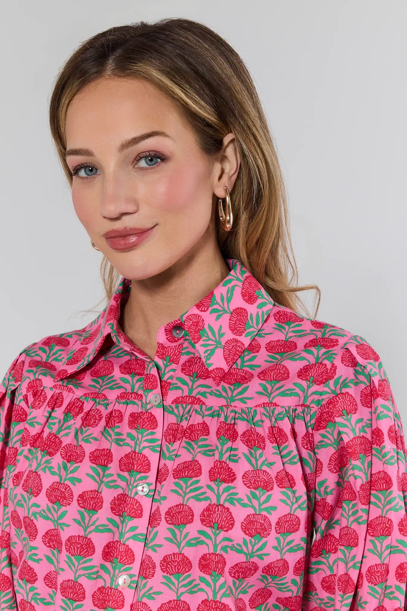 Woman wearing a pink floral patterned shirt against a plain background