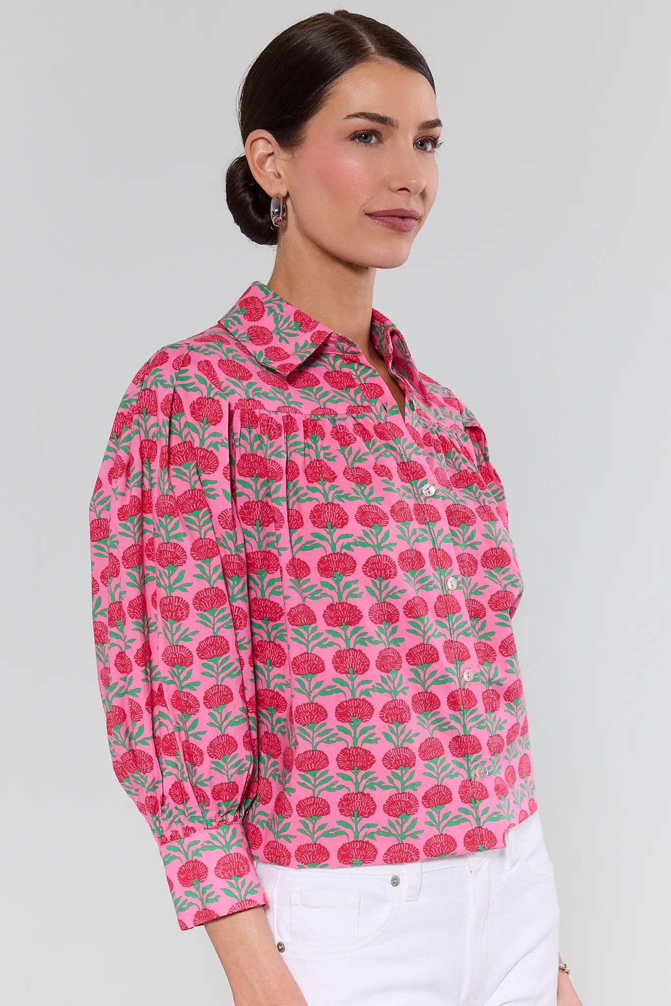Woman wearing a pink floral patterned shirt against a gray background