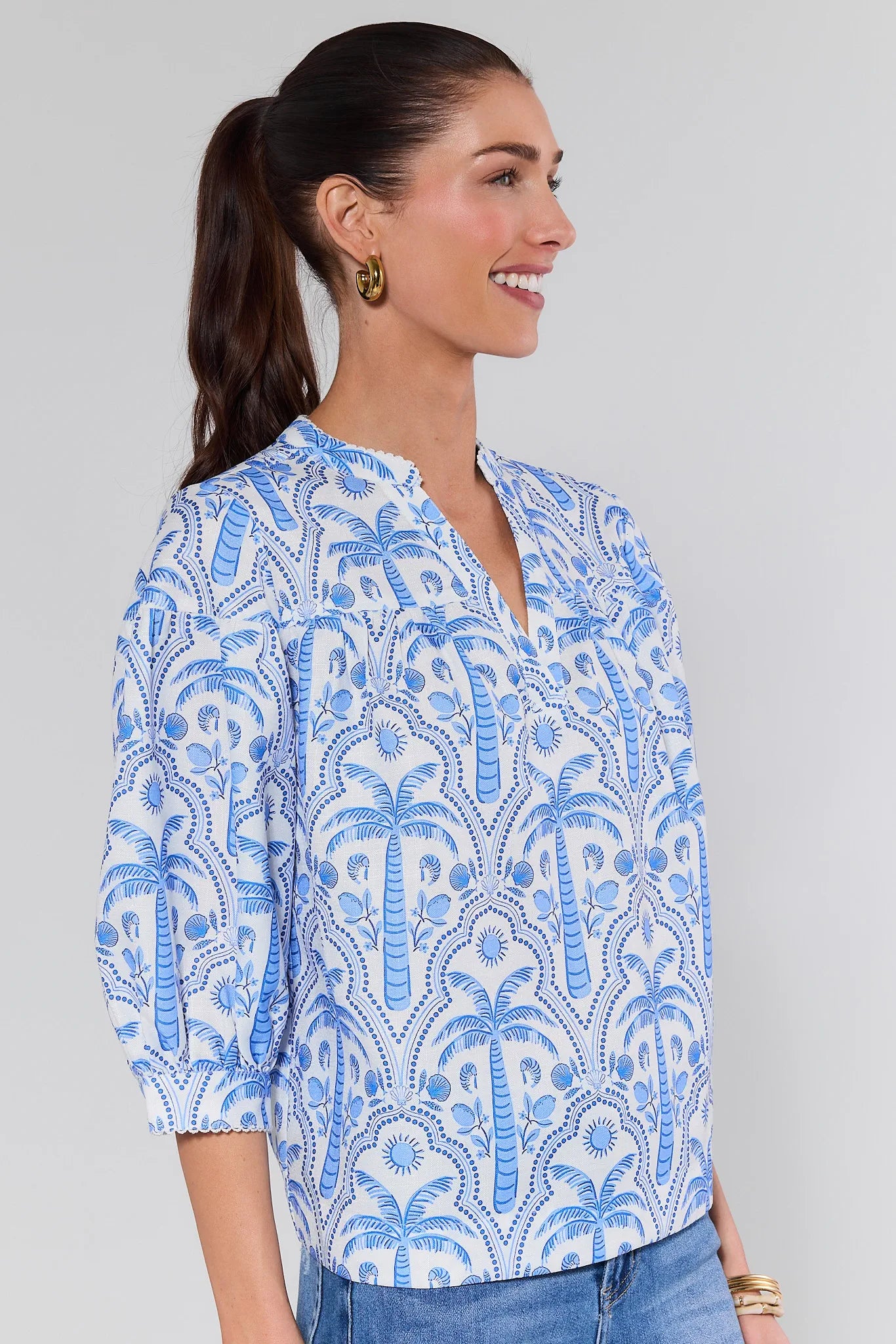 Woman wearing a blue and white patterned blouse against a gray background
