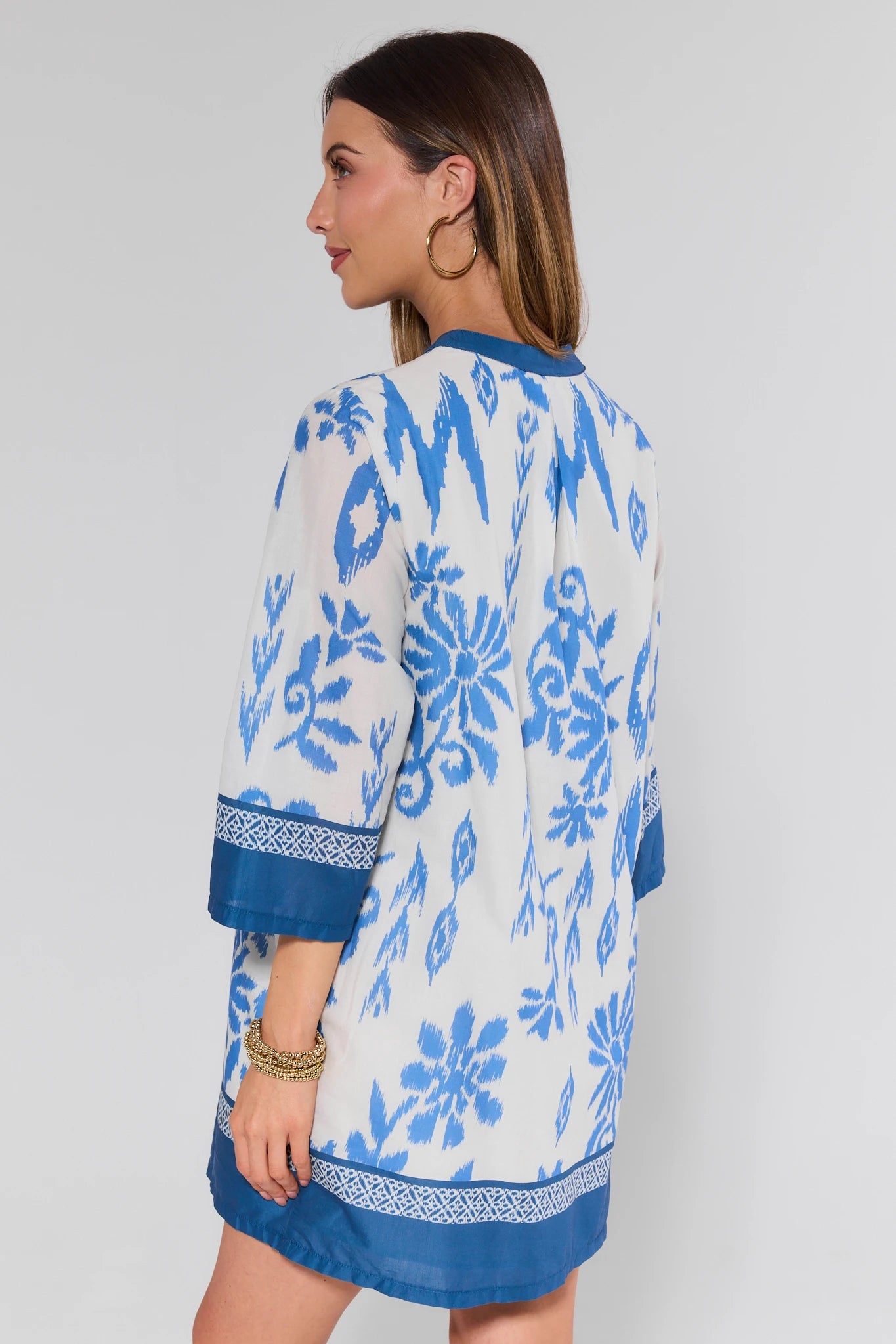 Woman wearing a blue and white floral patterned dress on a plain background