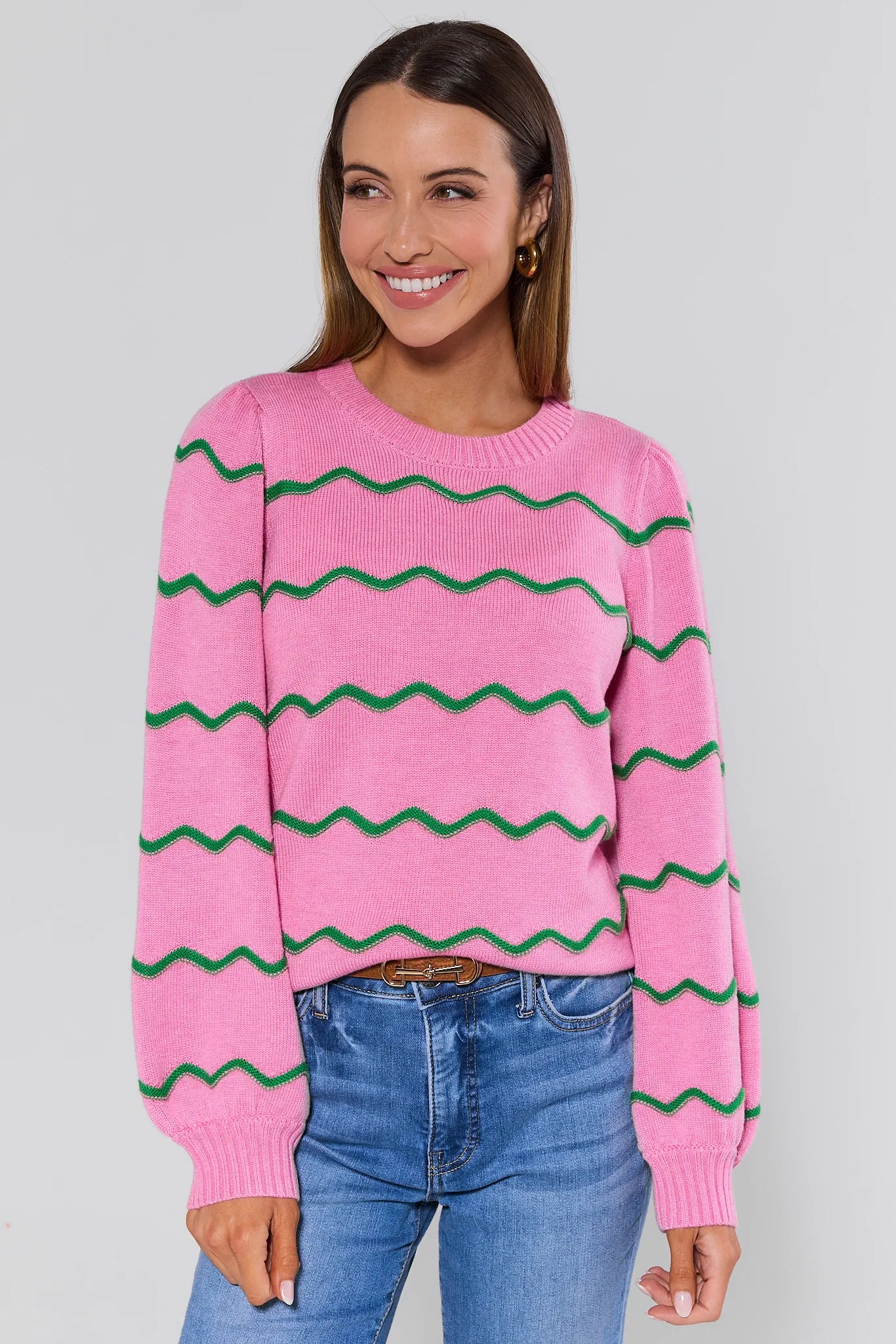 Woman wearing a pink sweater with green zigzag pattern against a gray background