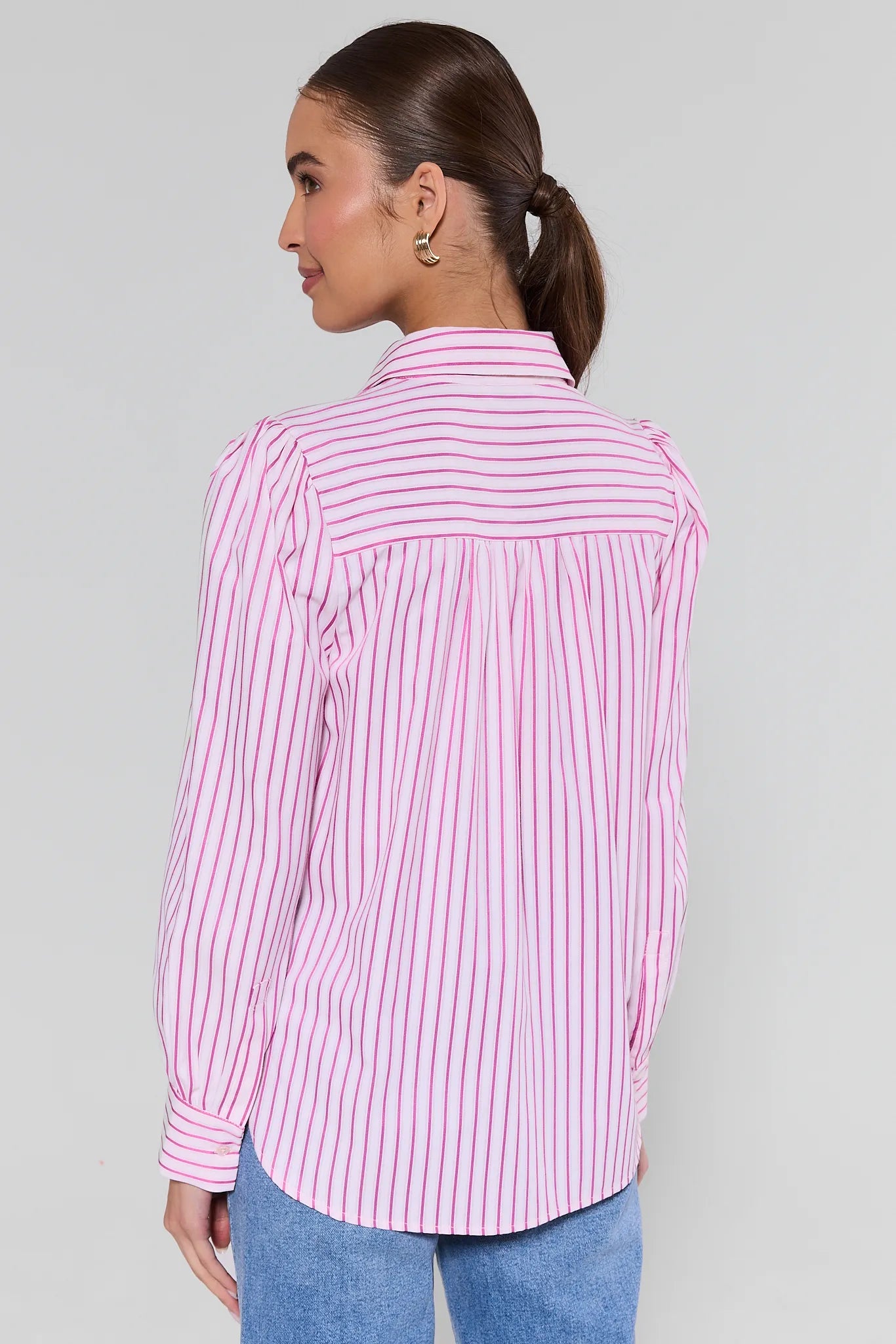 Woman wearing a pink and white striped shirt against a gray background