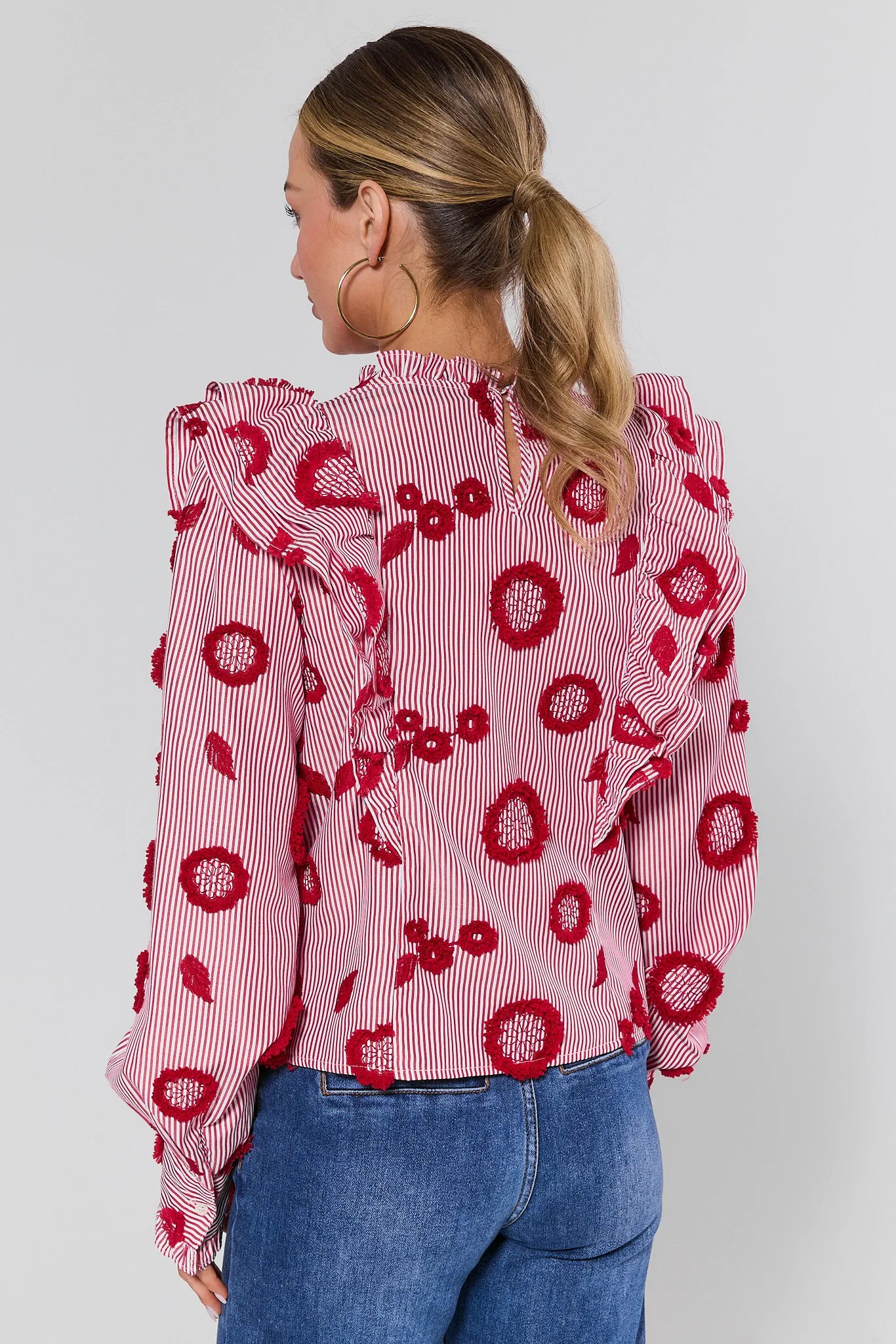 Woman wearing a red floral blouse with blue jeans on a white background