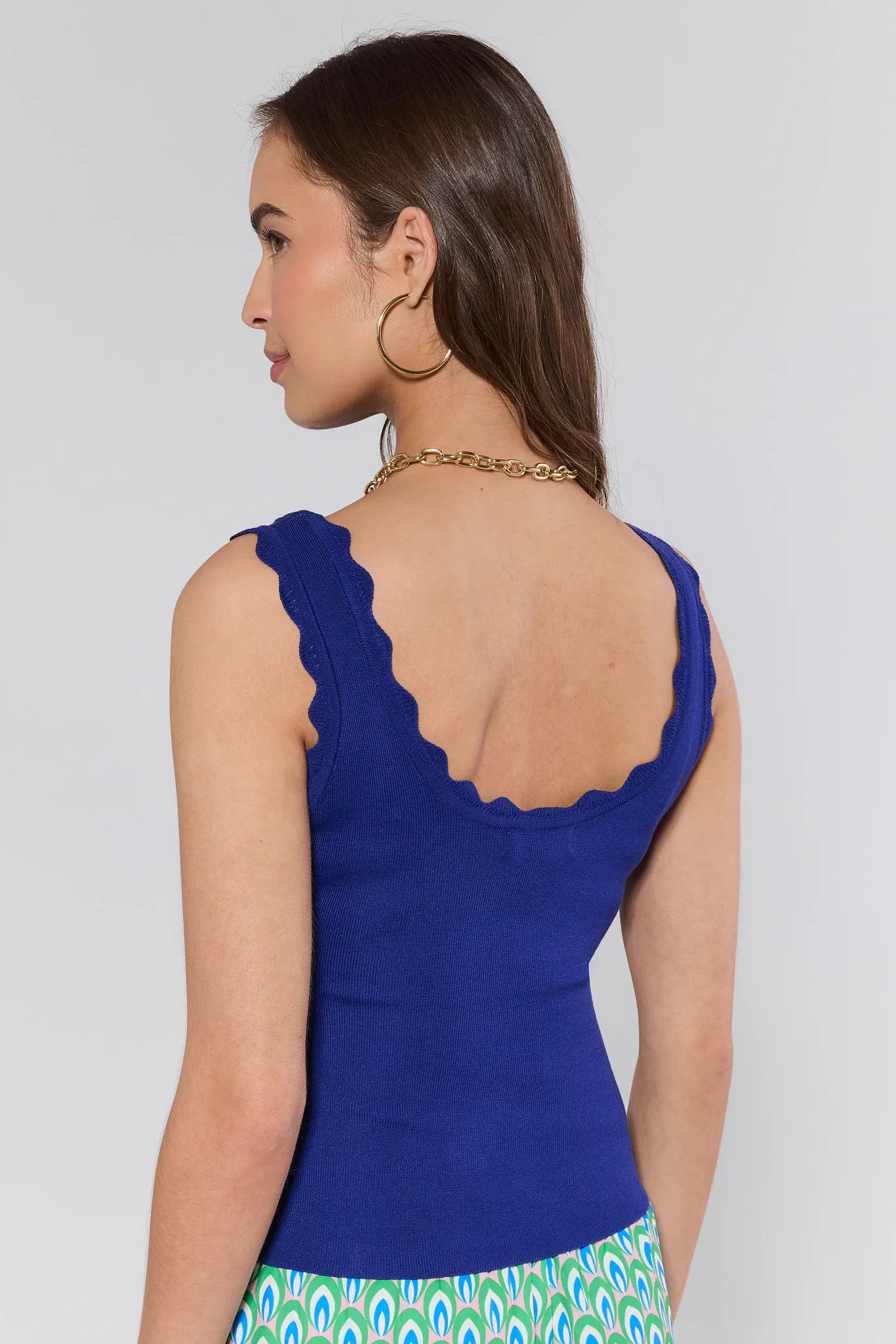 Woman wearing a blue sleeveless top with a white background