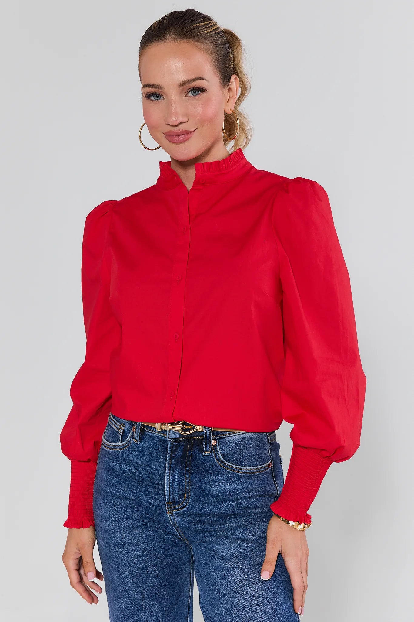 Woman wearing a Della Red Button Up Top and blue jeans against a plain background