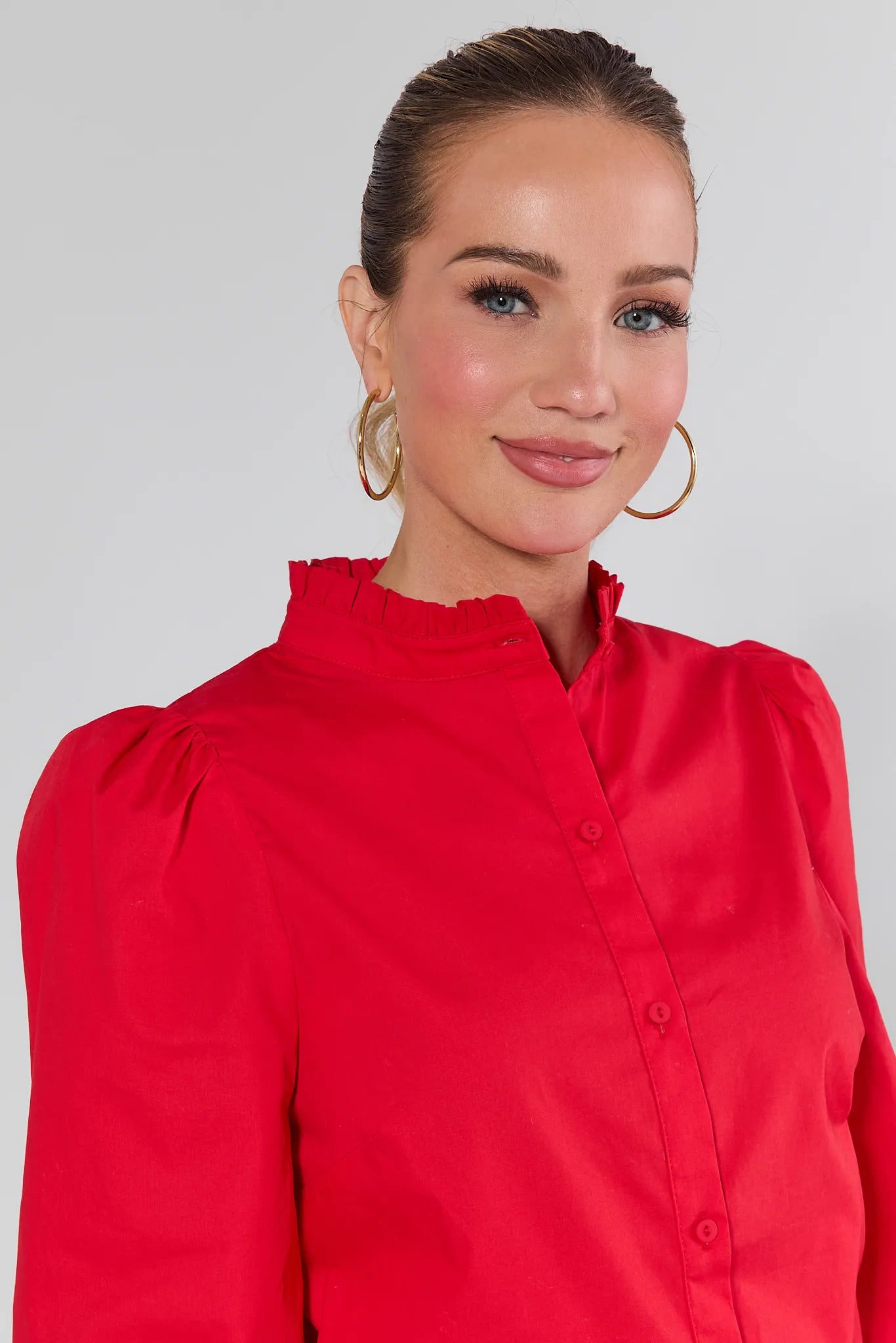 Woman wearing a Della Red Button Up Top and blue jeans against a plain background