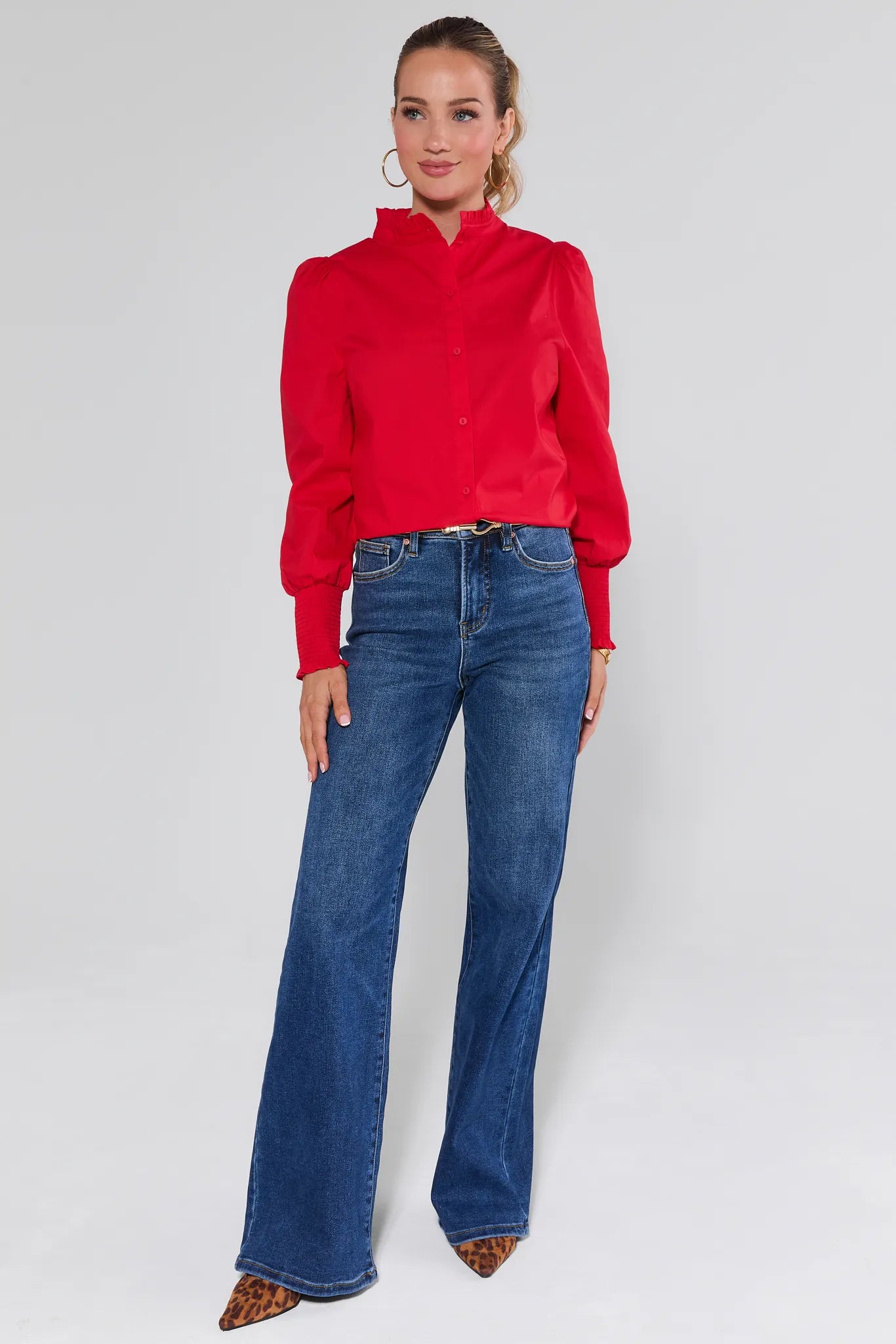 Woman wearing a Della Red Button Up Top and blue jeans against a plain background