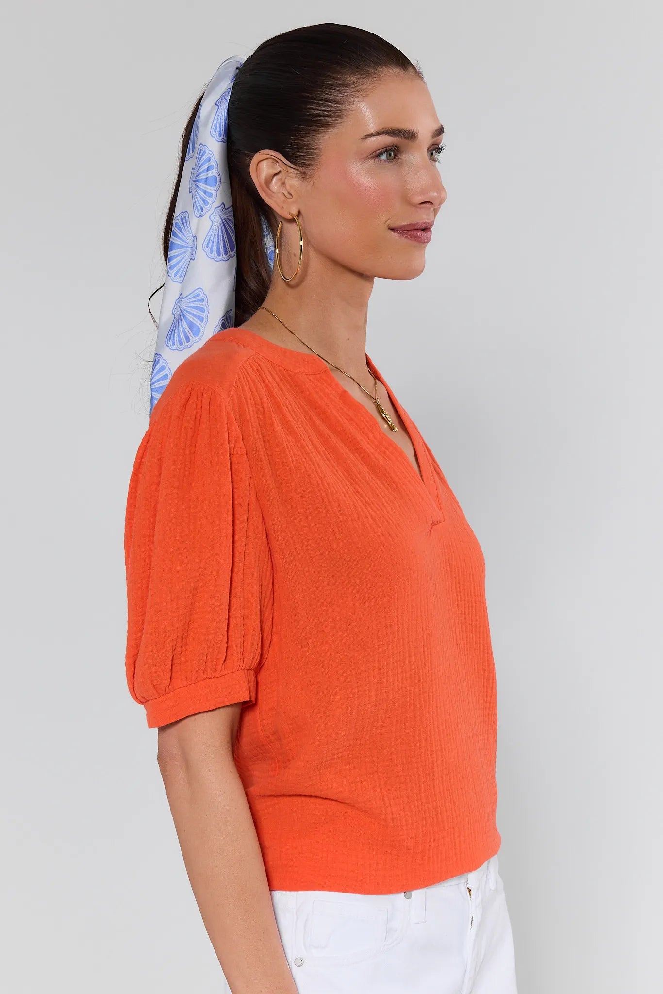 Woman wearing an orange top with a white background