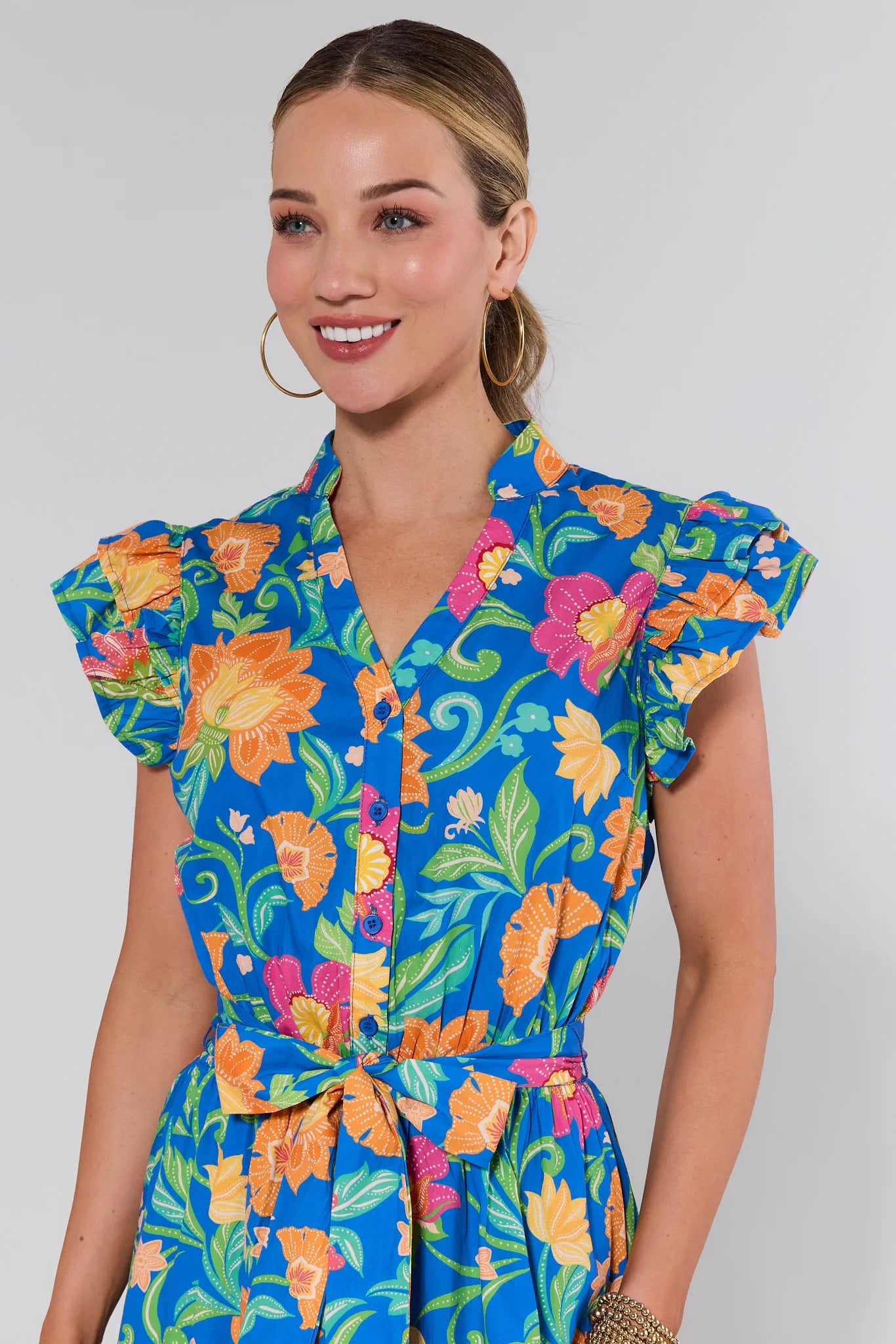 Woman wearing a colorful floral dress against a plain background