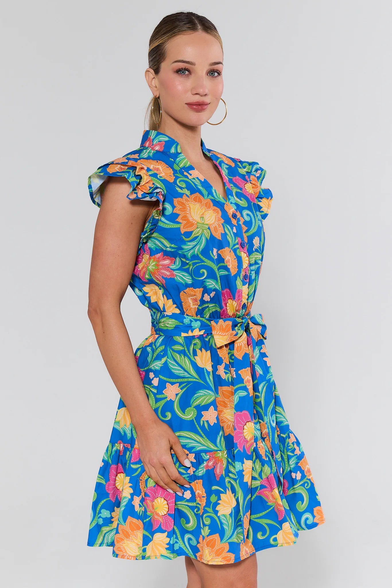 Woman wearing a colorful floral dress on a plain background