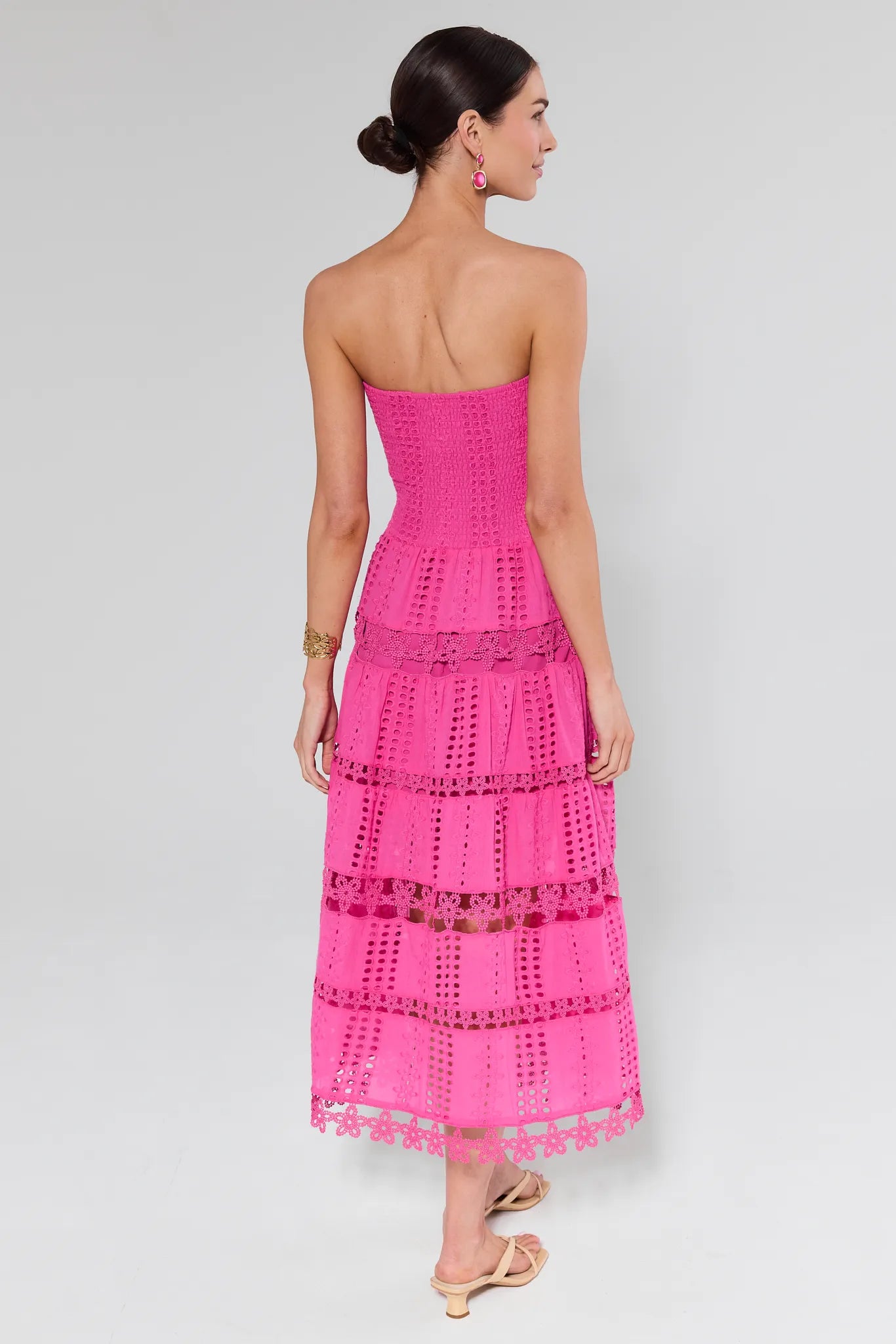 Woman wearing a pink strapless dress with lace details on a white background