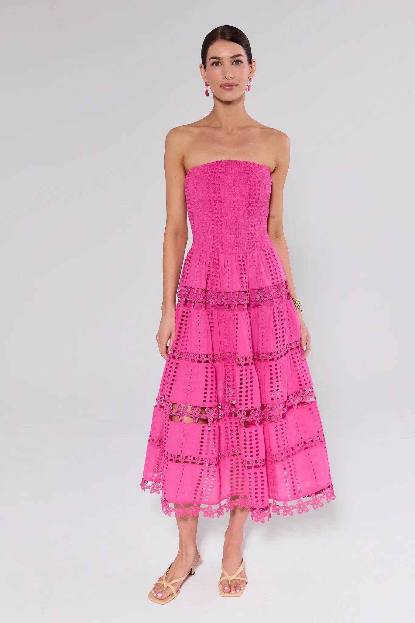 Woman wearing a pink strapless dress with lace details on a white background