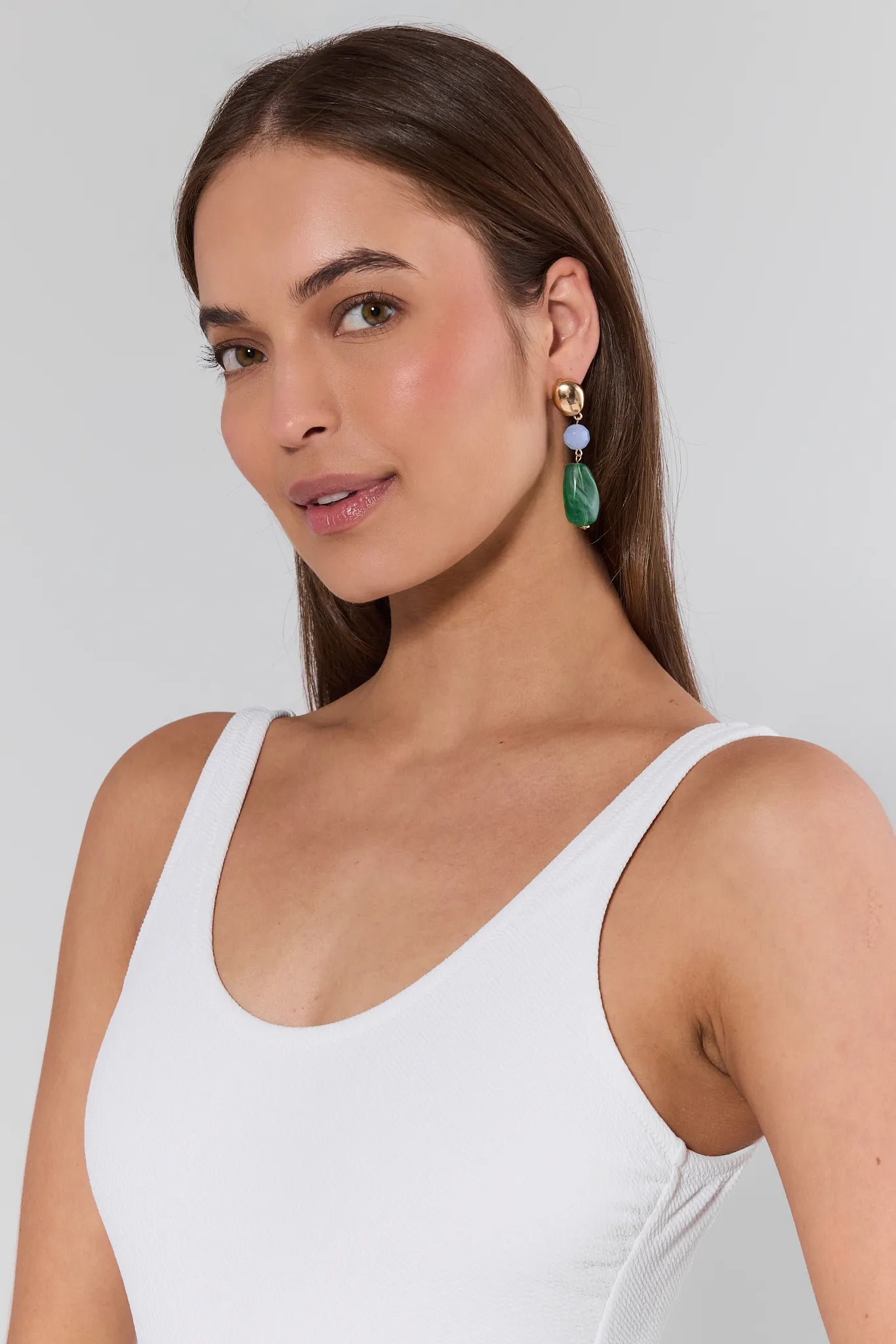 Woman wearing a white tank top with a plain background