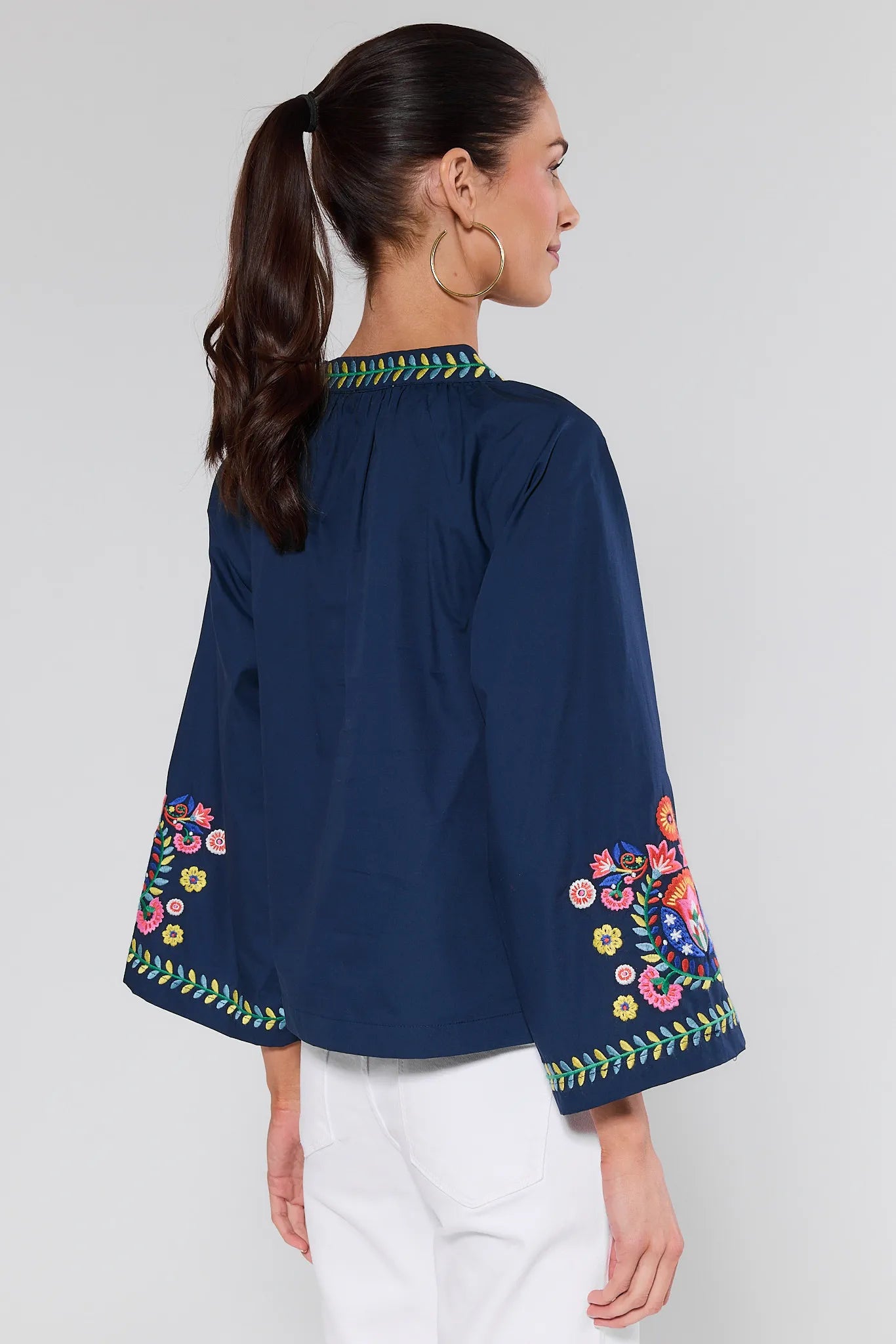 Navy blue blouse with colorful floral embroidery on sleeves and neckline against a white background