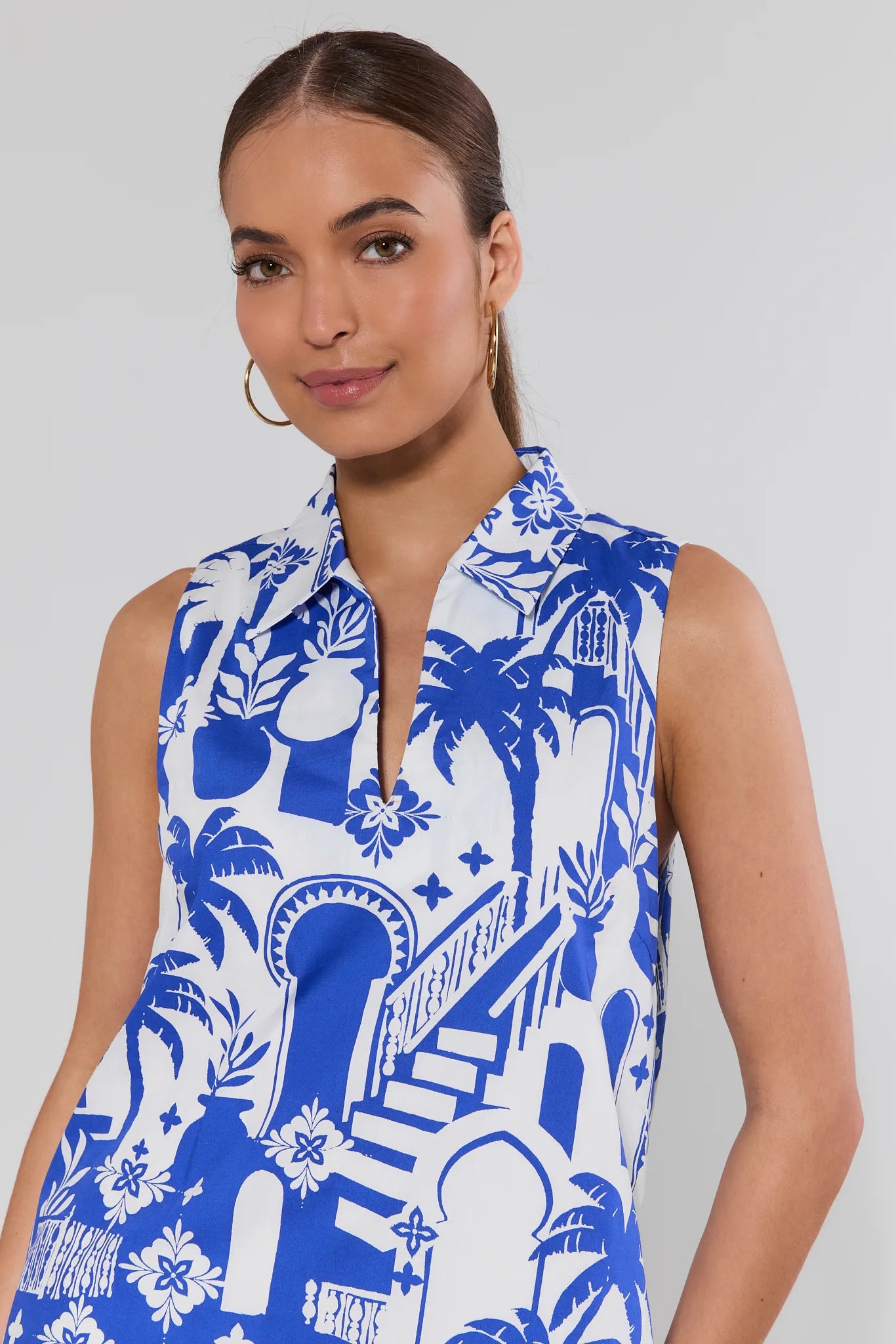 Woman wearing a blue and white patterned sleeveless dress against a plain background