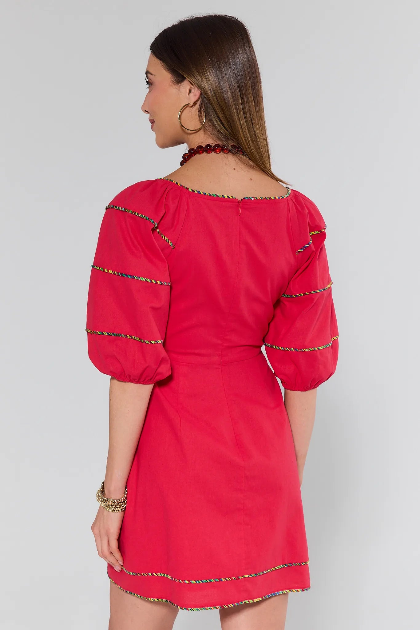 Red dress with trim worn by a person on a white background