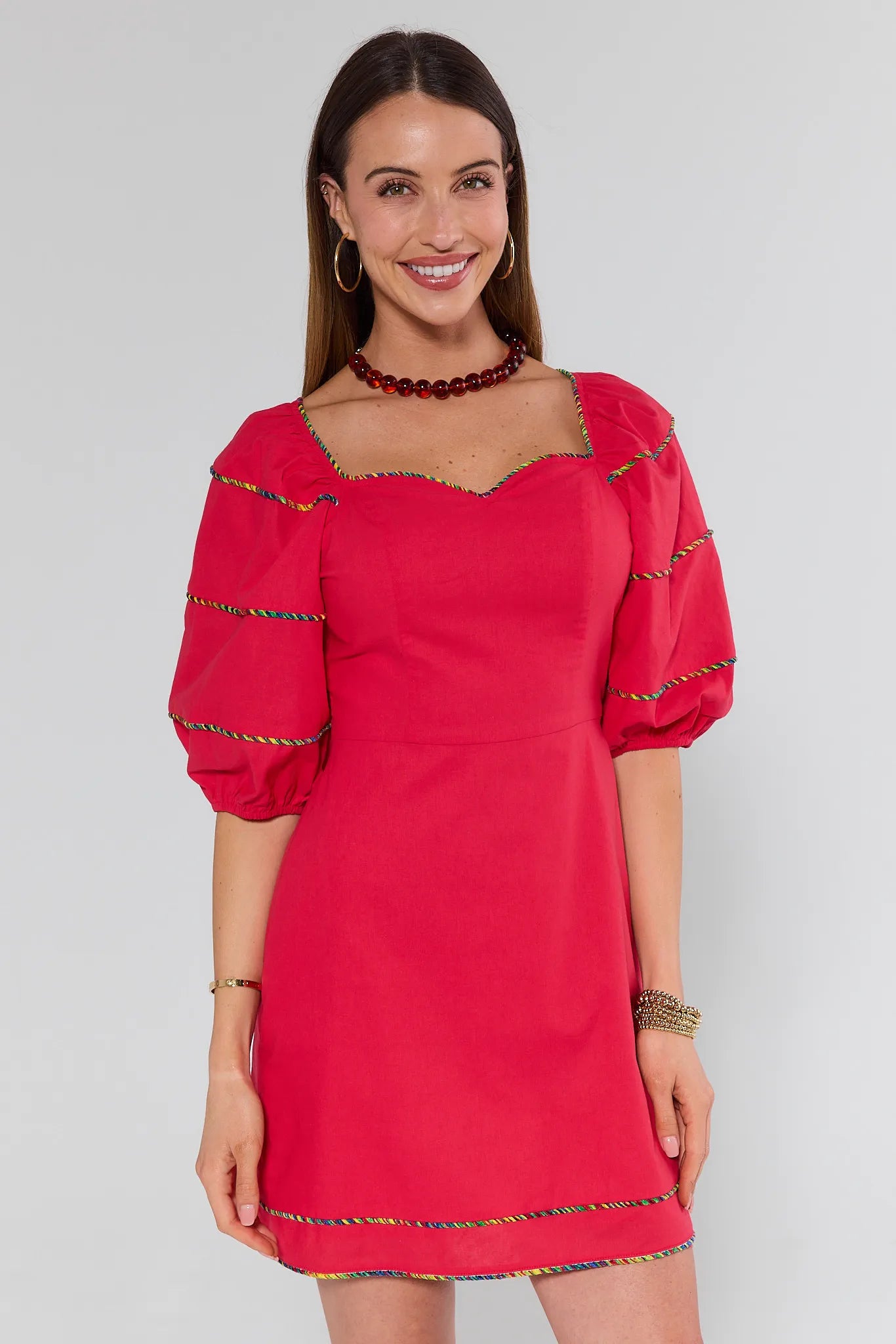 Woman wearing a red dress with gold trim on a white background