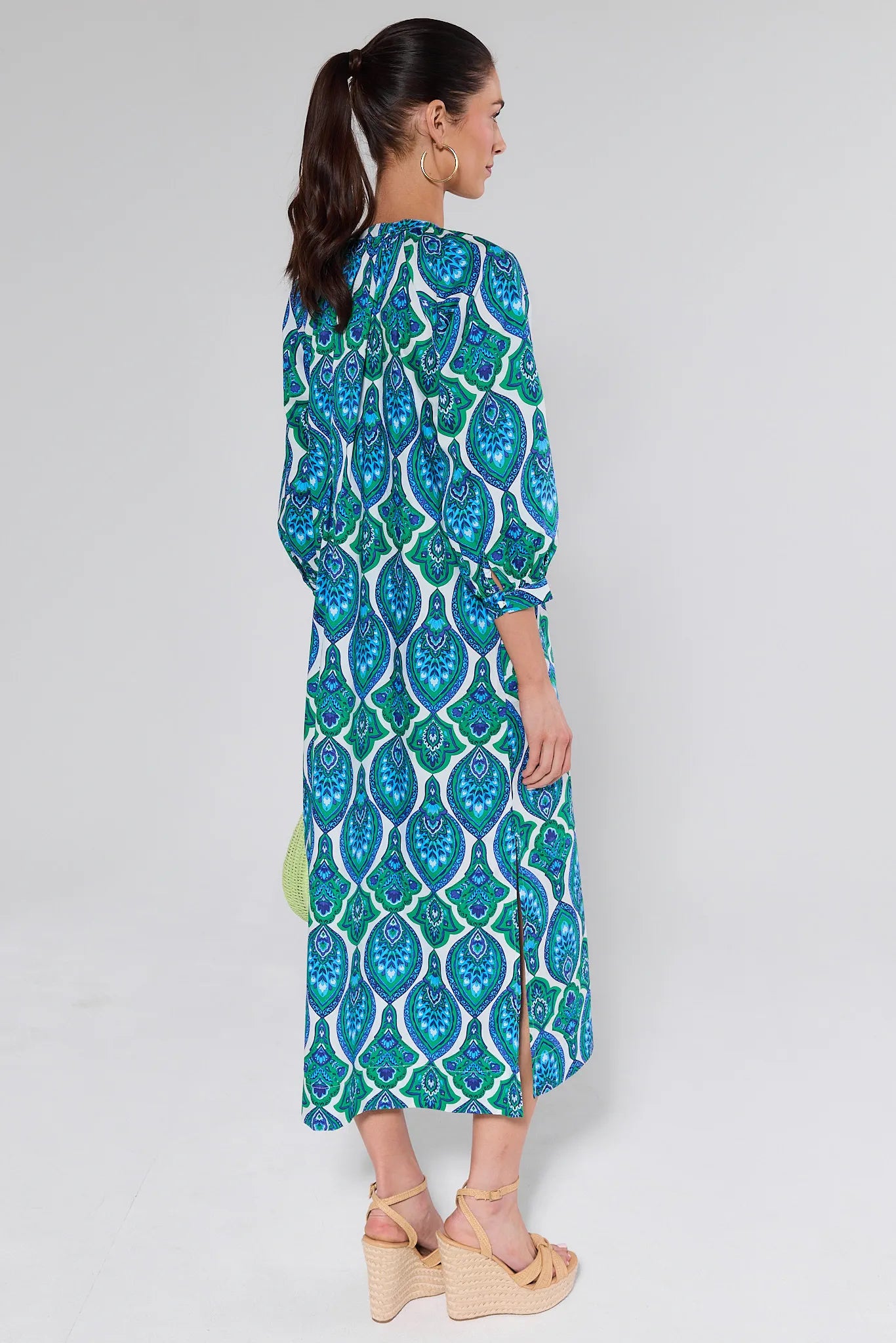 Woman wearing a blue and green patterned dress on a white background