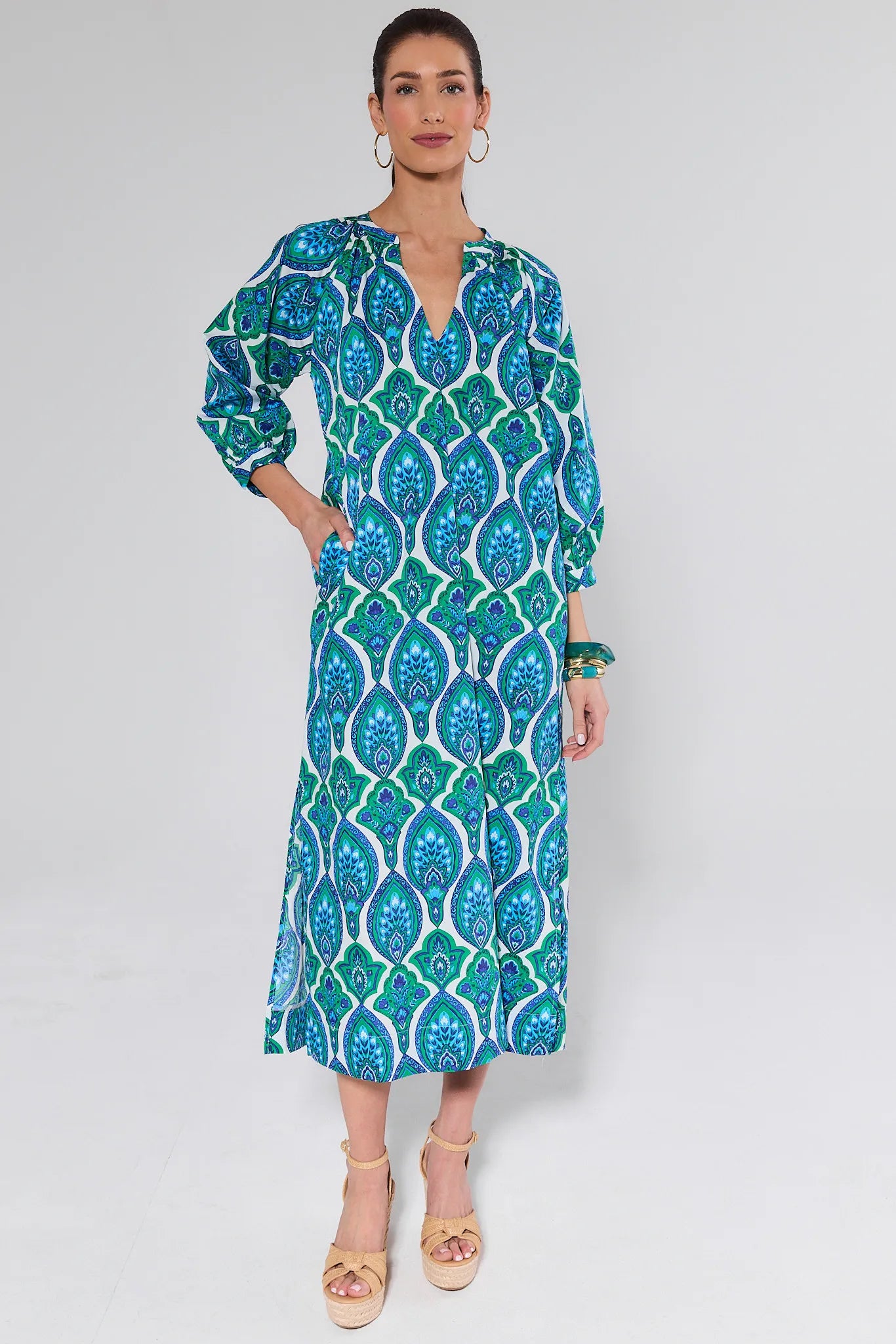 Woman wearing a blue and green patterned dress on a white background