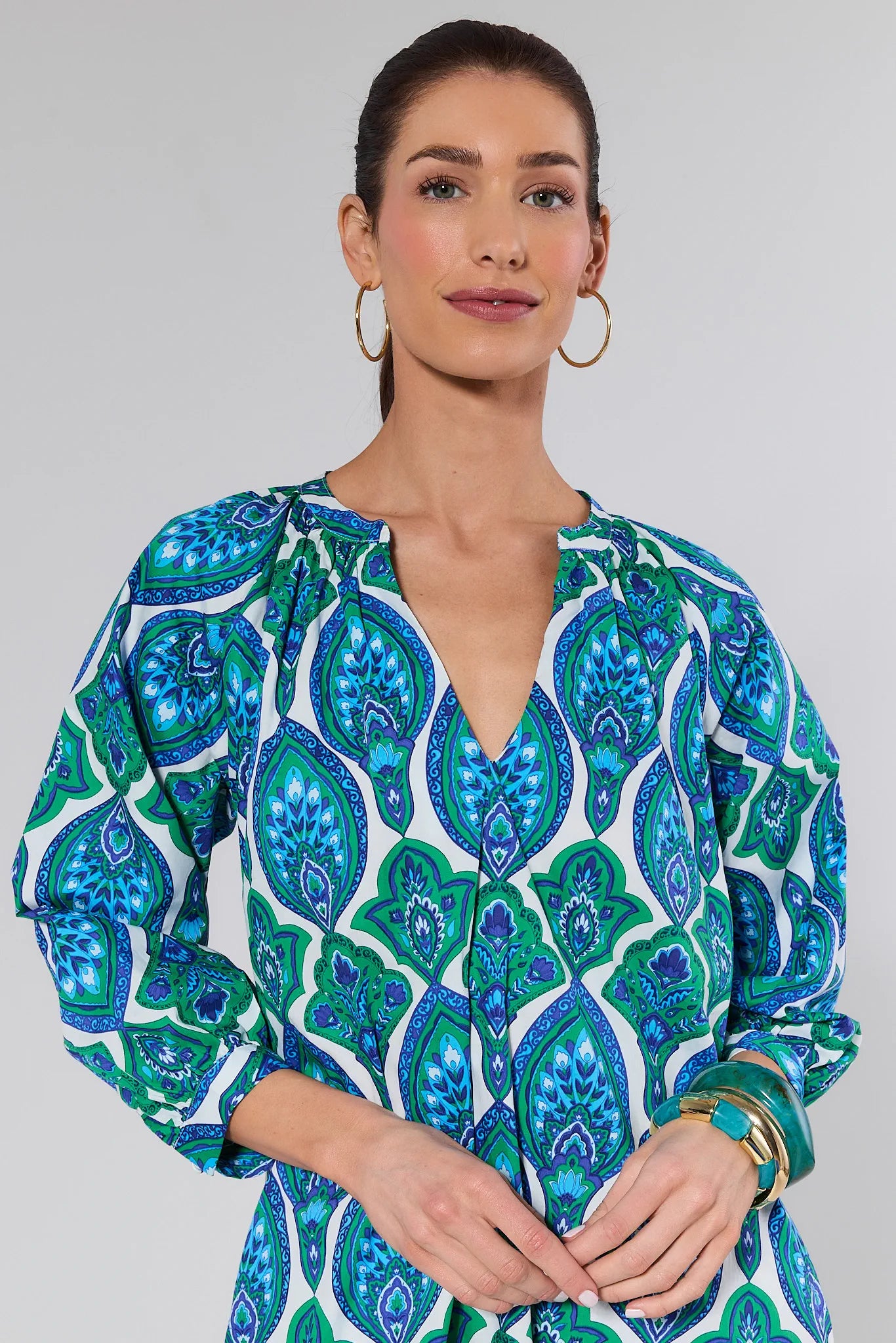 Woman wearing a blue and green patterned dress against a background