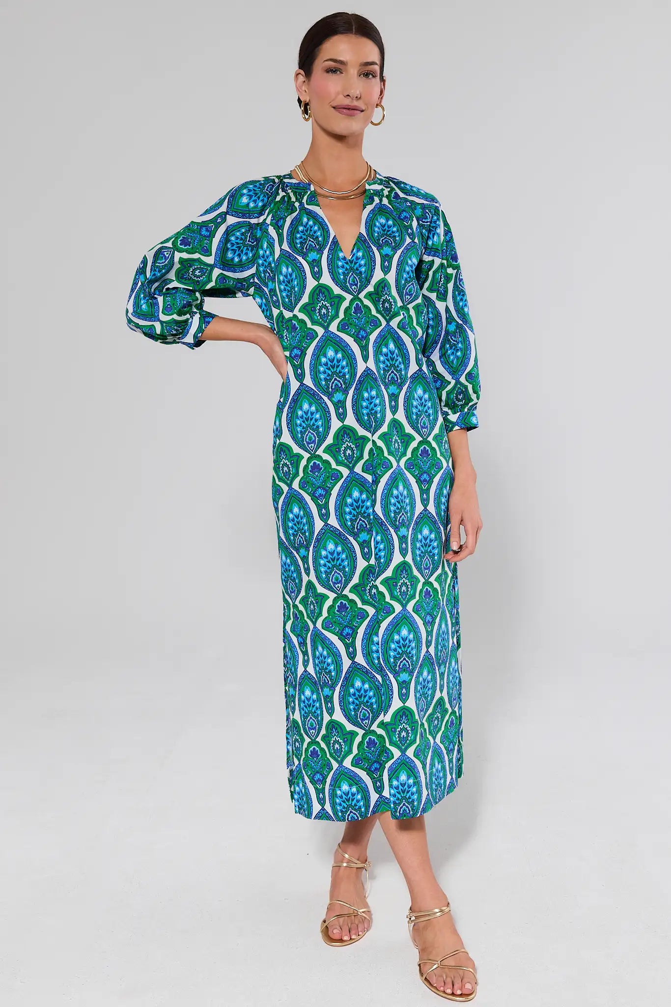 Woman wearing a green and blue patterned ellie dress on a white background