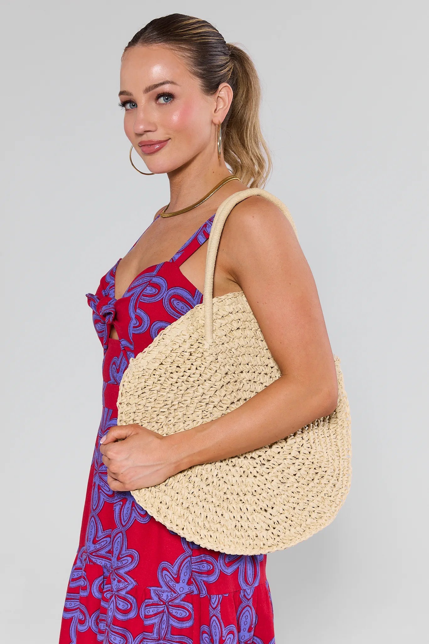 Woman holding a Josie Raffia Woven Bucket Bag against a plain background