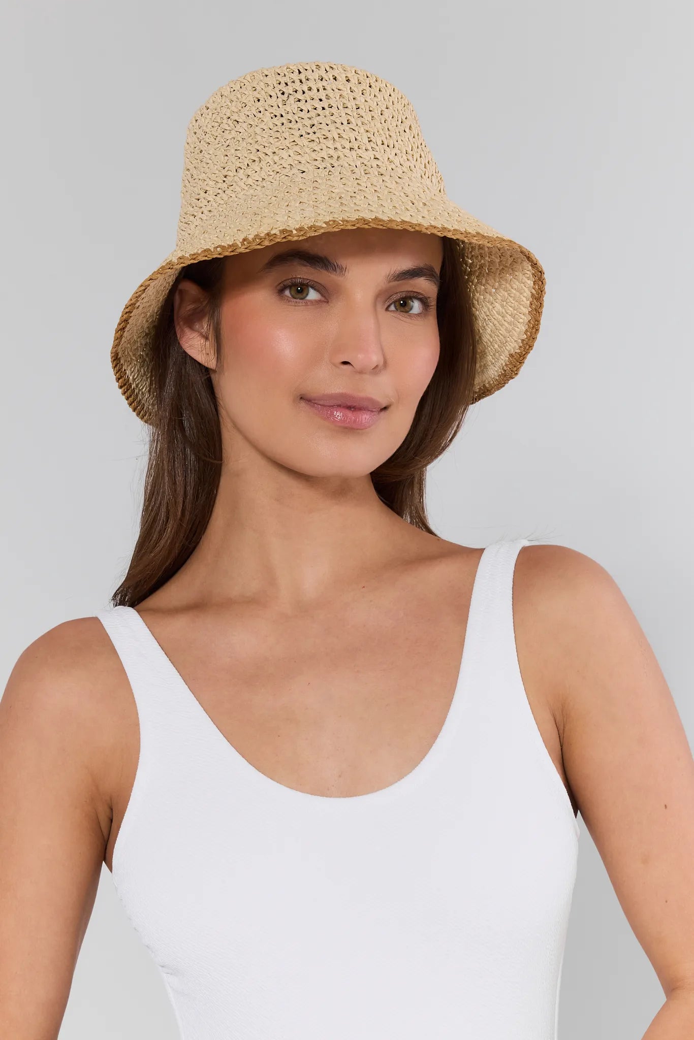 Woman wearing a straw hat against a plain background
