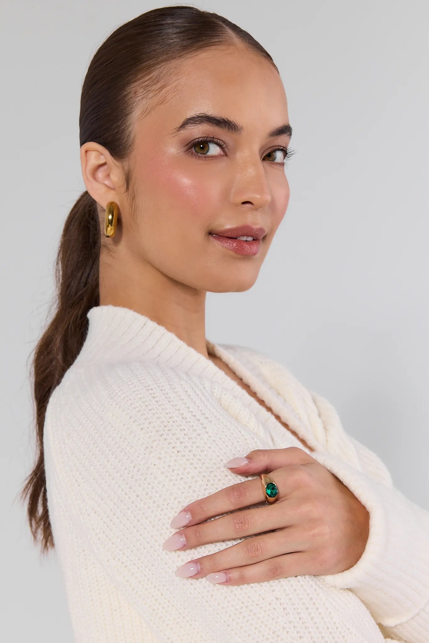 Woman wearing a white sweater with a plain background