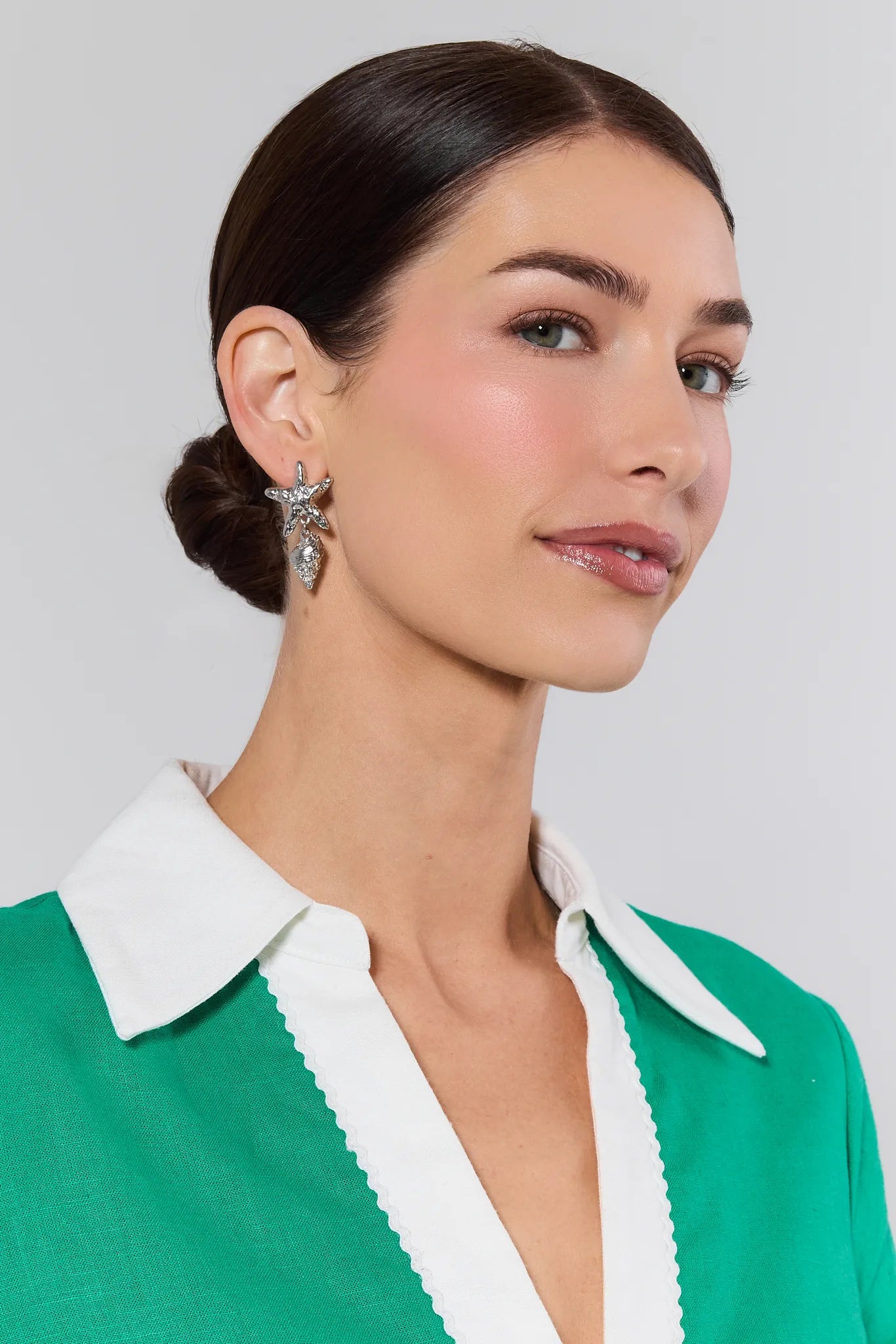 Silver Shell earrings on women plain background