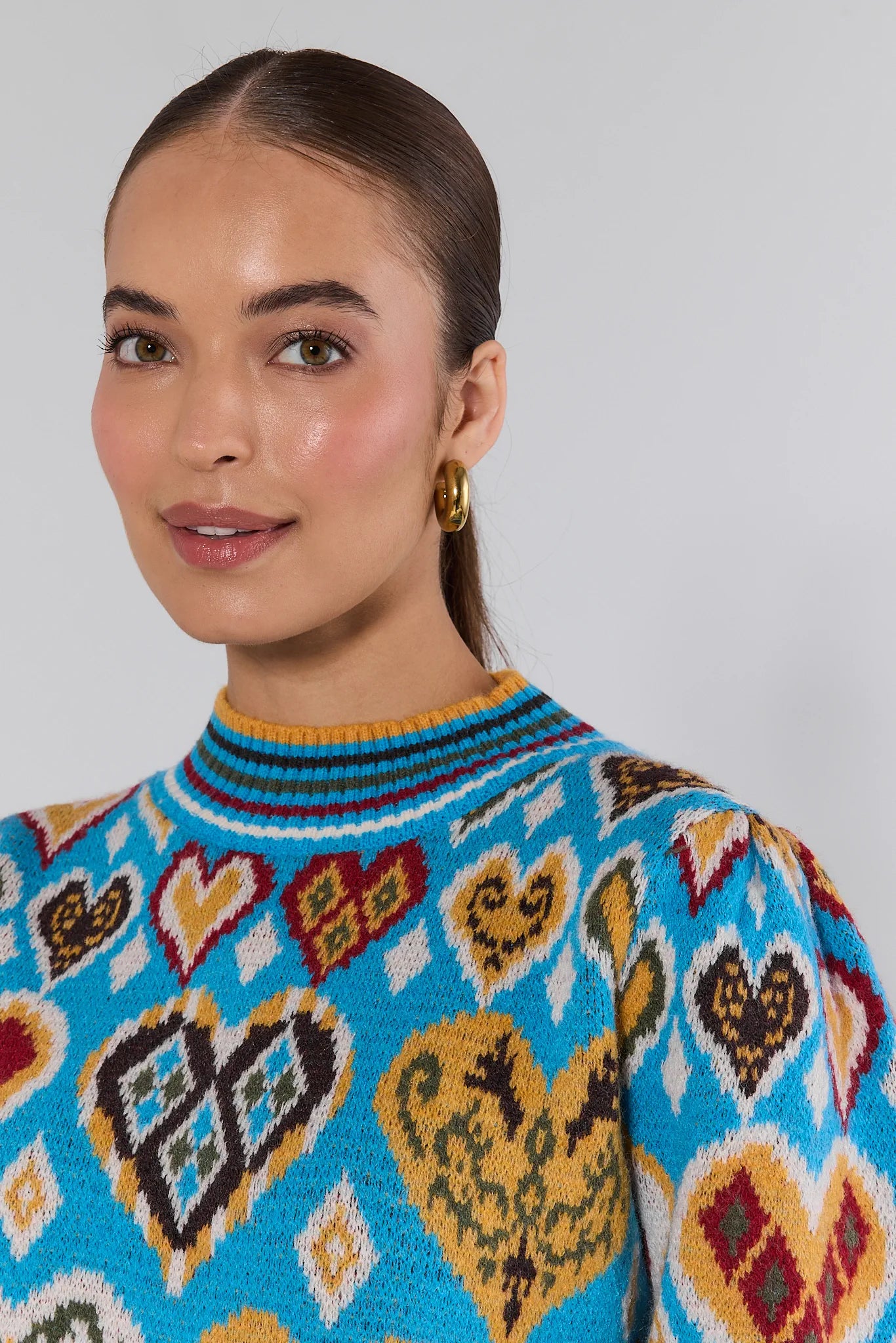 Woman wearing a Cammie Blue Heart Knit Sweater against a plain background