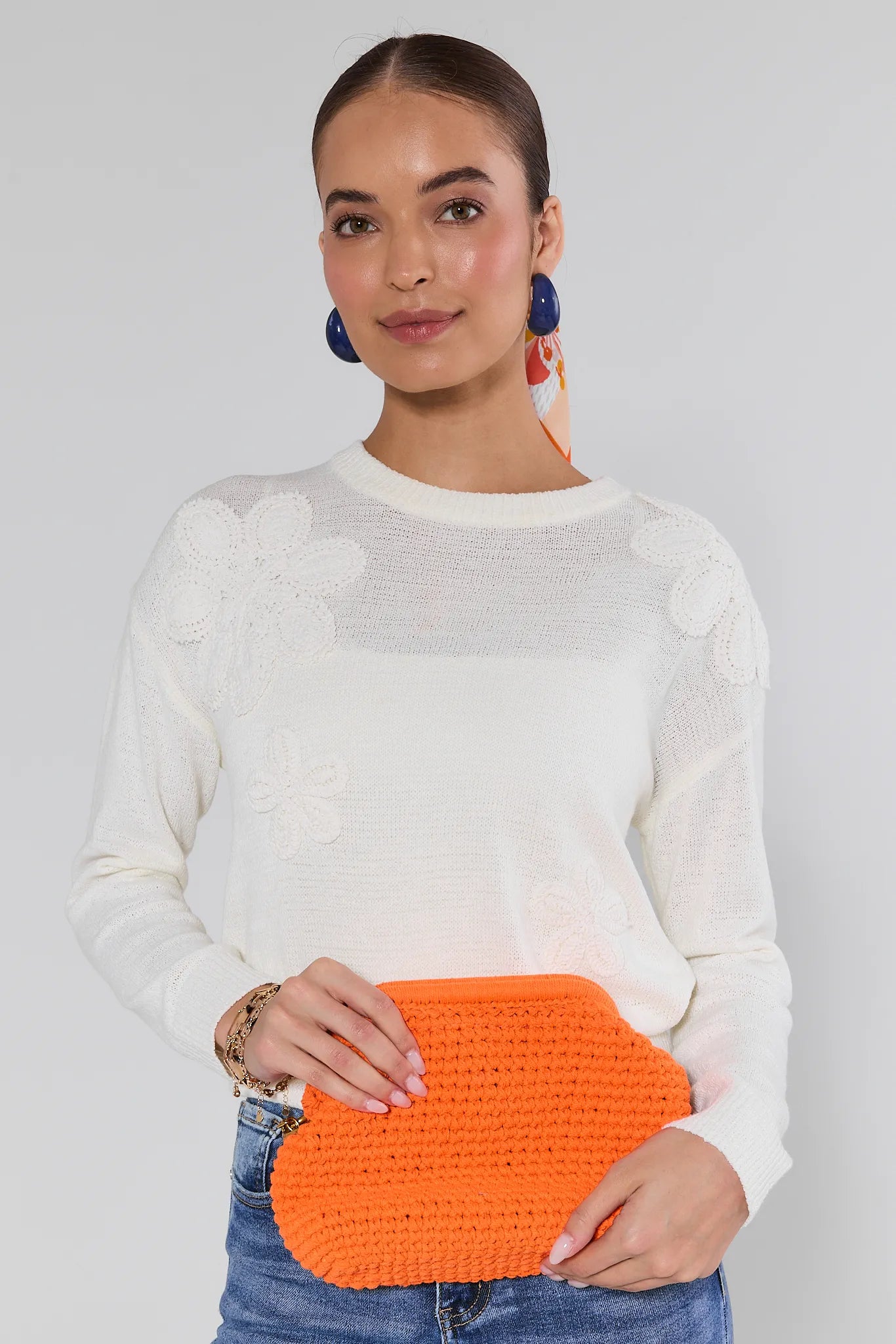 Woman holding a Gabbie Orange Crochet Shoulder Bag against a plain background
