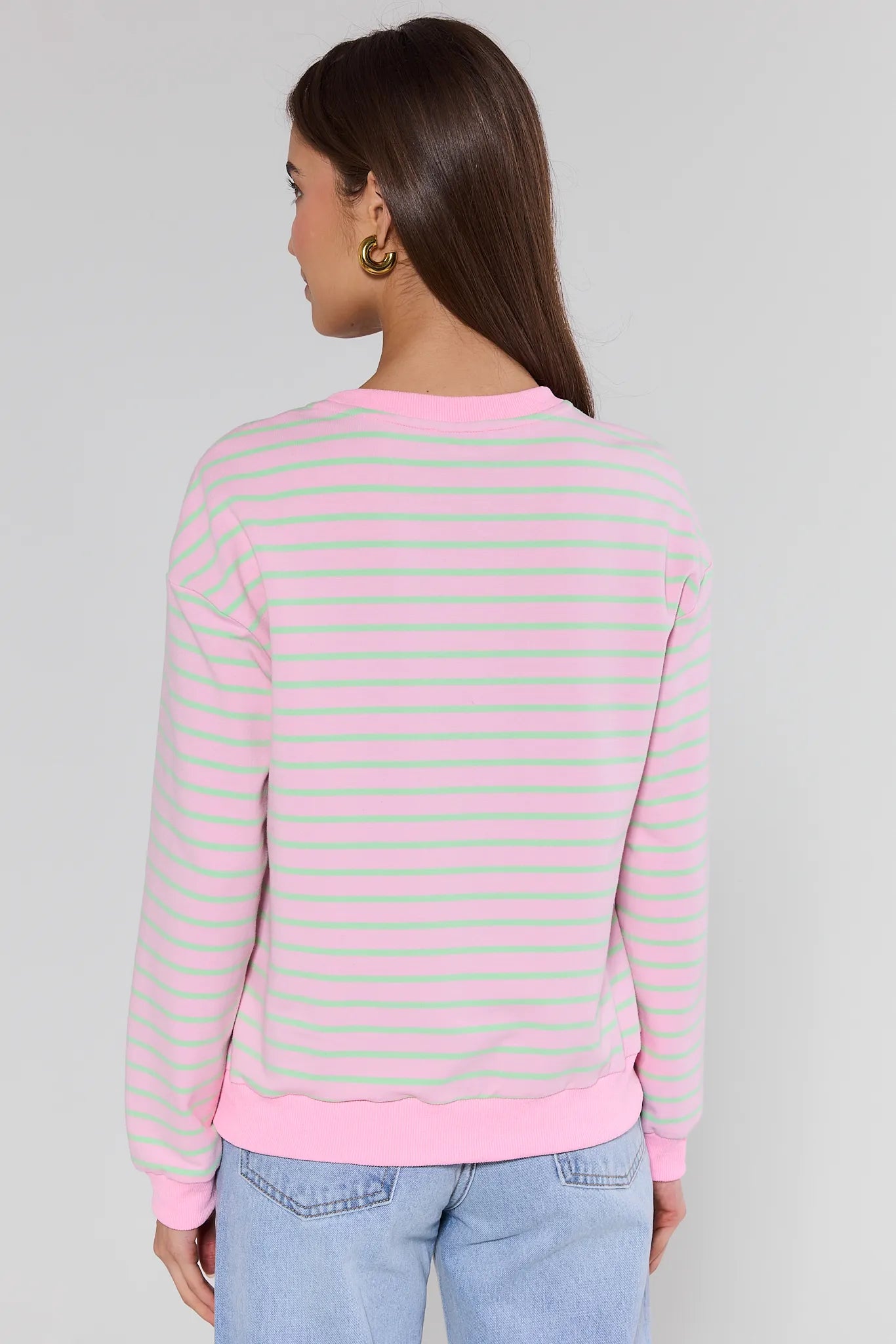Woman wearing a pink and green striped sweater against a gray background