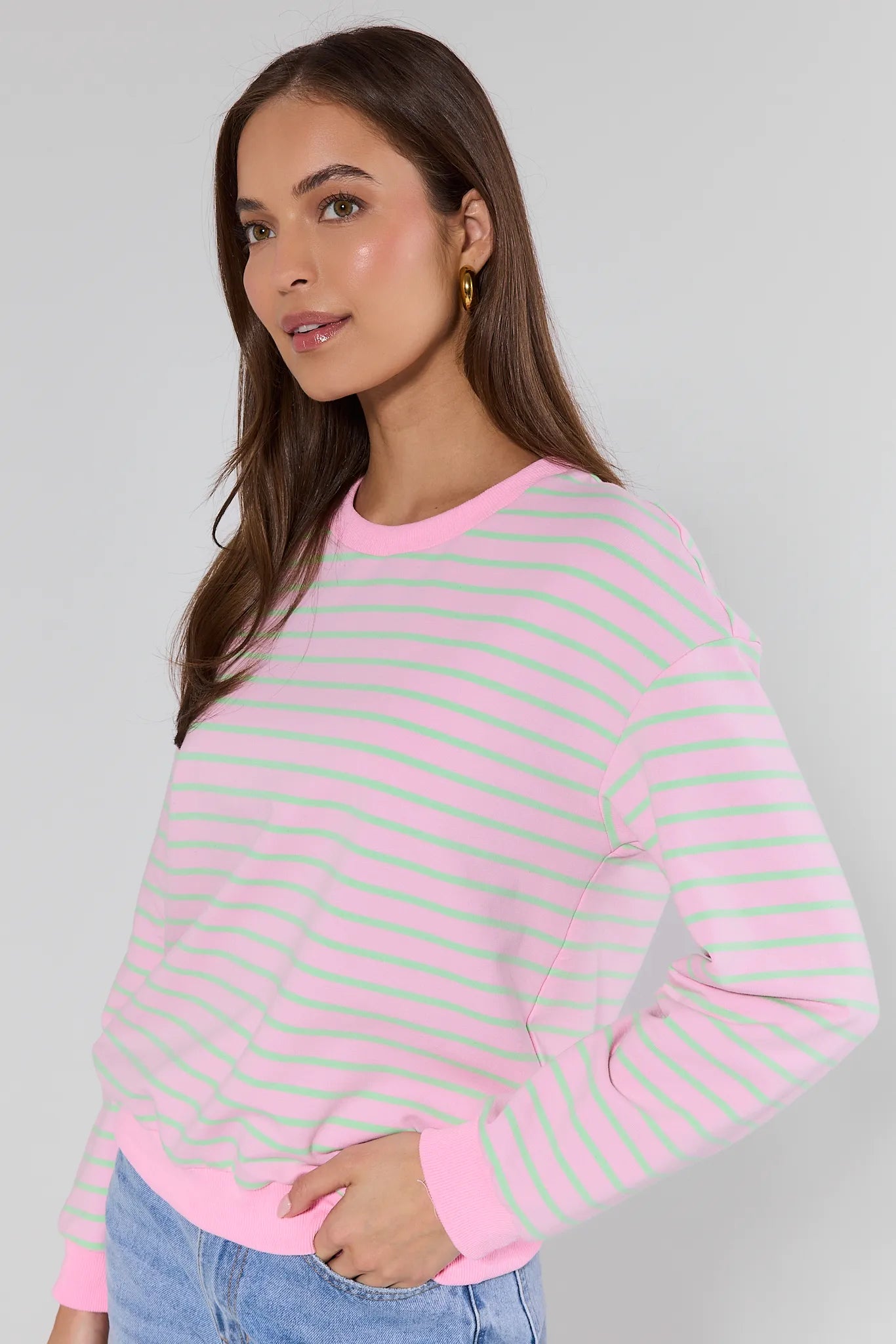 Woman wearing a pink and green striped sweater against a gray background