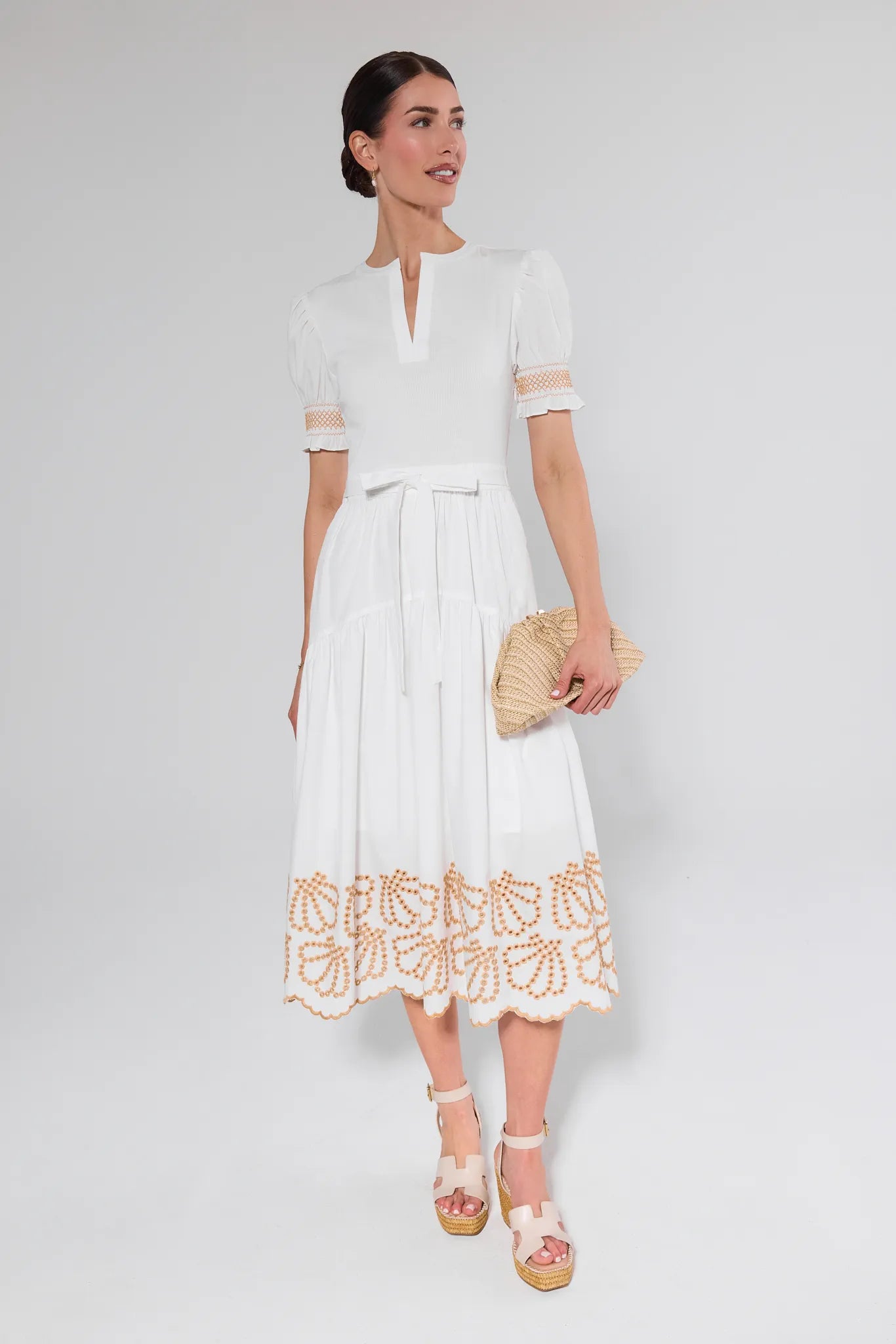 Woman wearing a white dress with lace details on a plain background