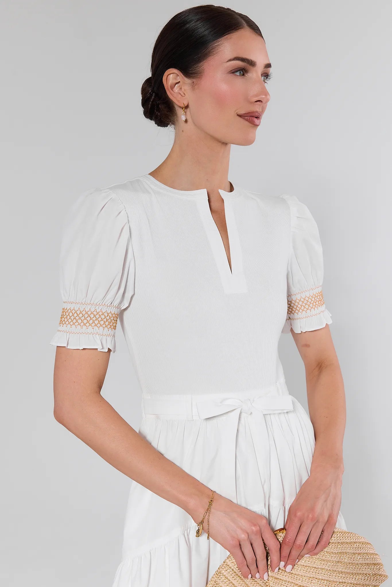 Woman wearing a white dress with lace details on a plain background