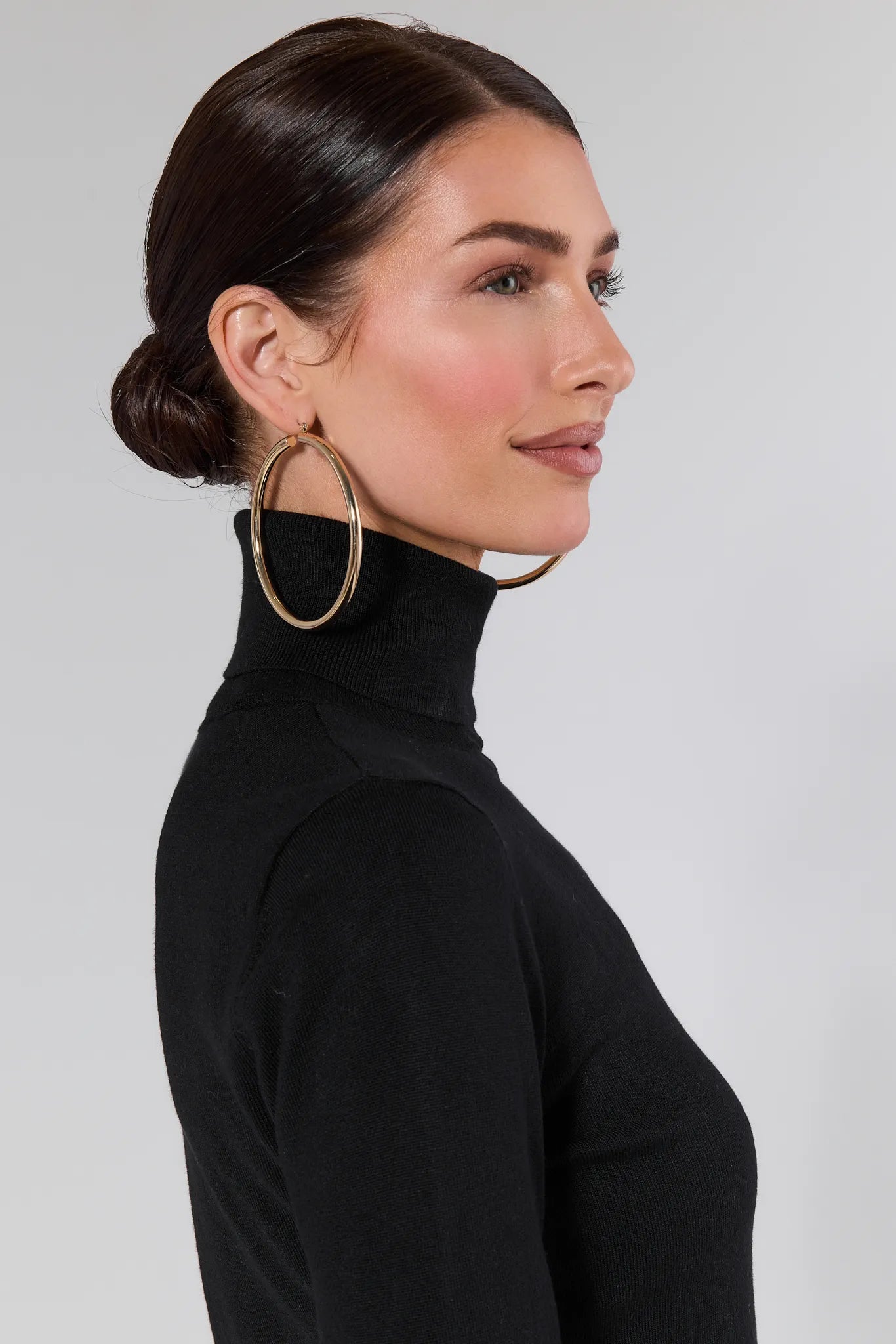 Woman wearing a Andrea Black Turtleneck Top and blue jeans against a plain background
