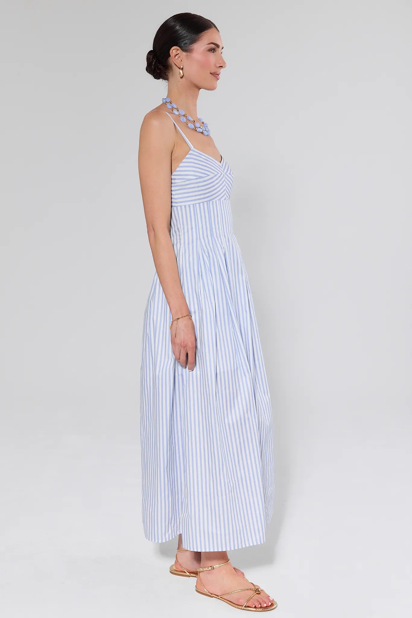 Woman wearing a blue and white striped dress against a white background