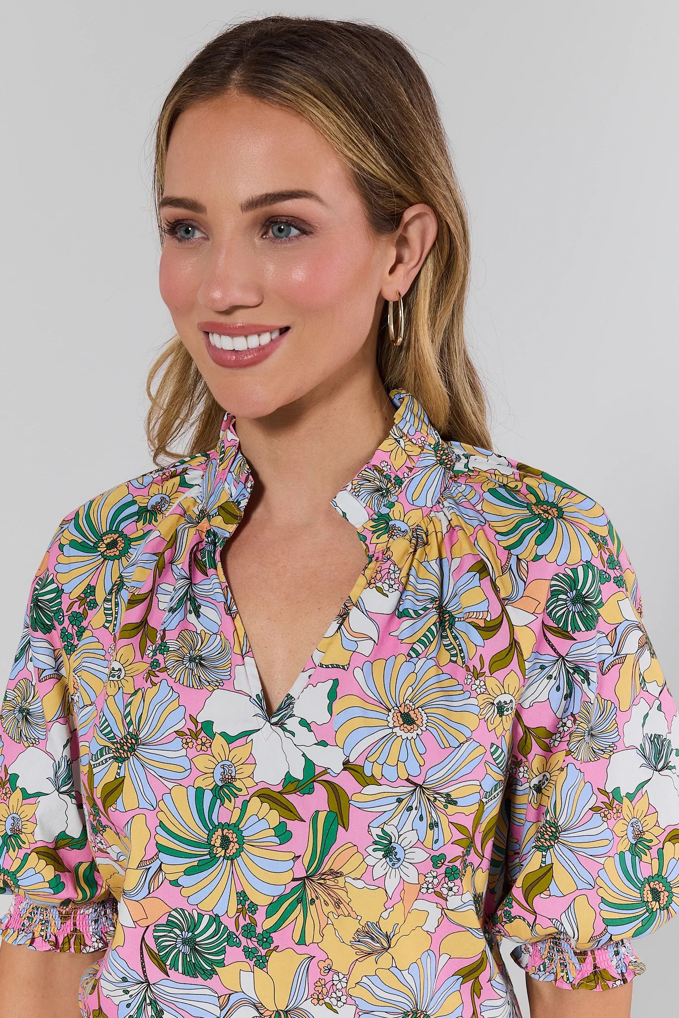 Woman wearing a colorful floral blouse against a plain background
